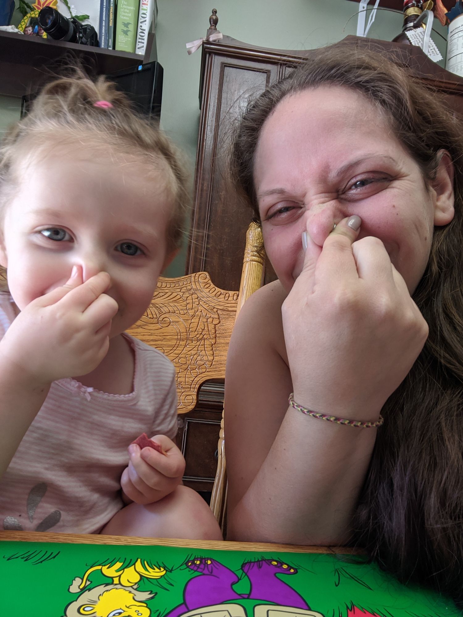 Selfie of mom and toddler holding noses and squinting with silly faces.