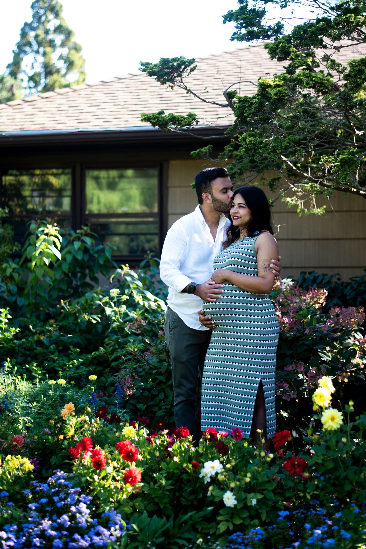 Portrait of man kissing his pregnant wife through the flowers at Deep Cut Gardens in New Jersey during maternity shoot.