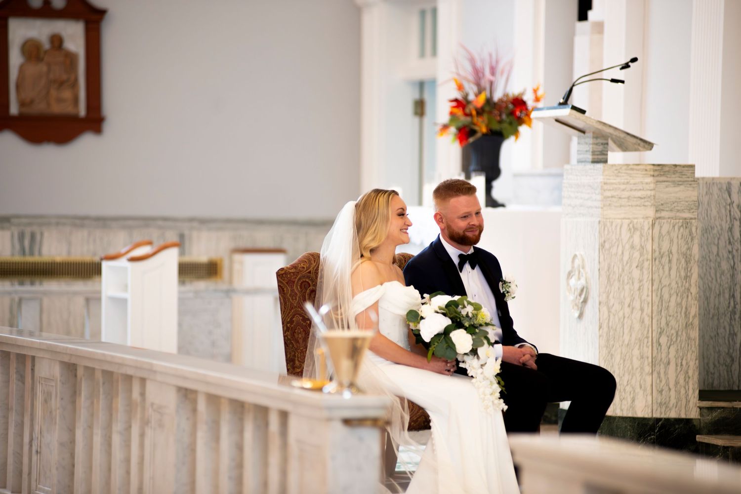 Bride and groom smile while sitting at altar during church ceremony in Pennsylvania.