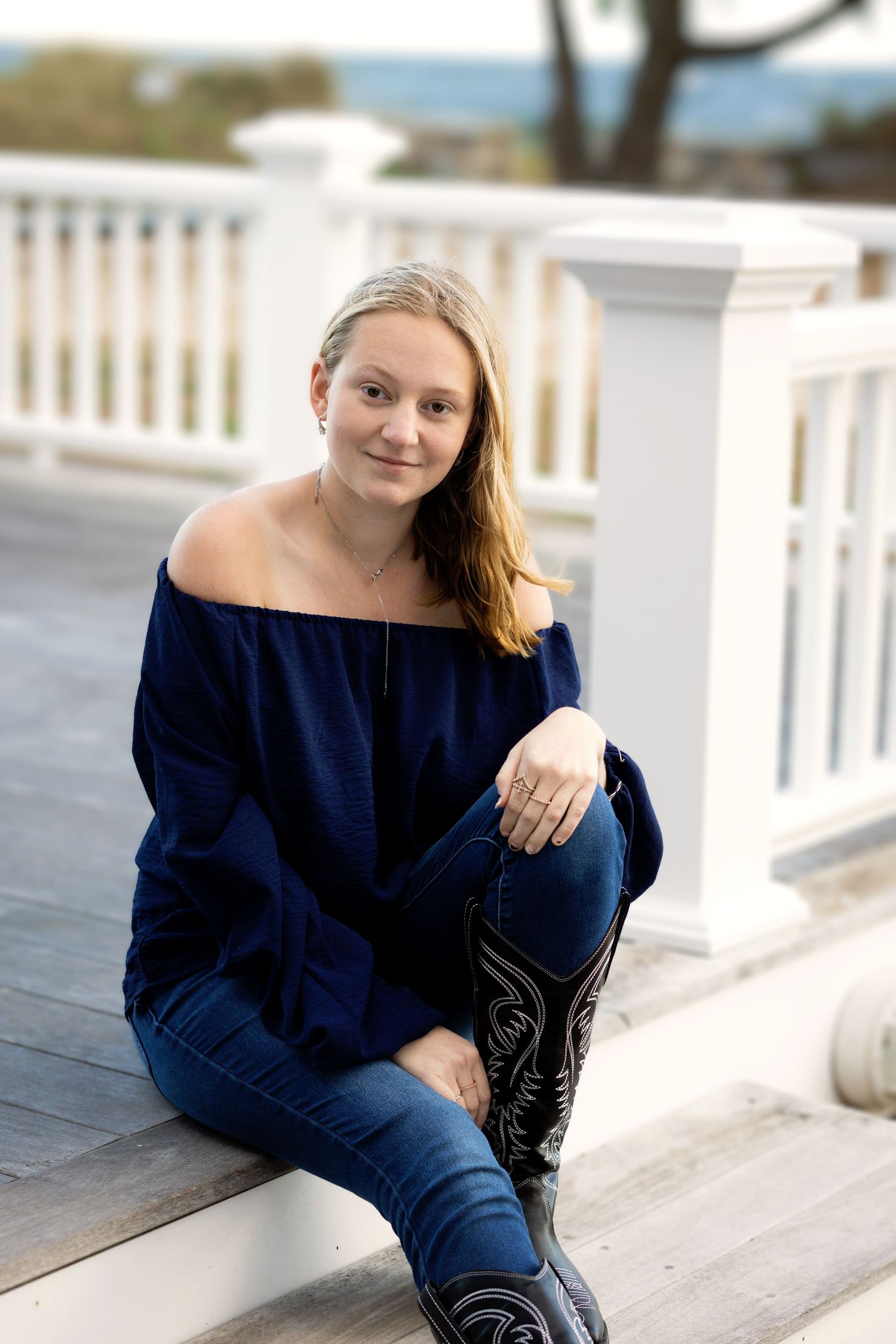 A series of outdoor portrait photos showing someone in a navy blue sweater sitting on white steps in natural light.