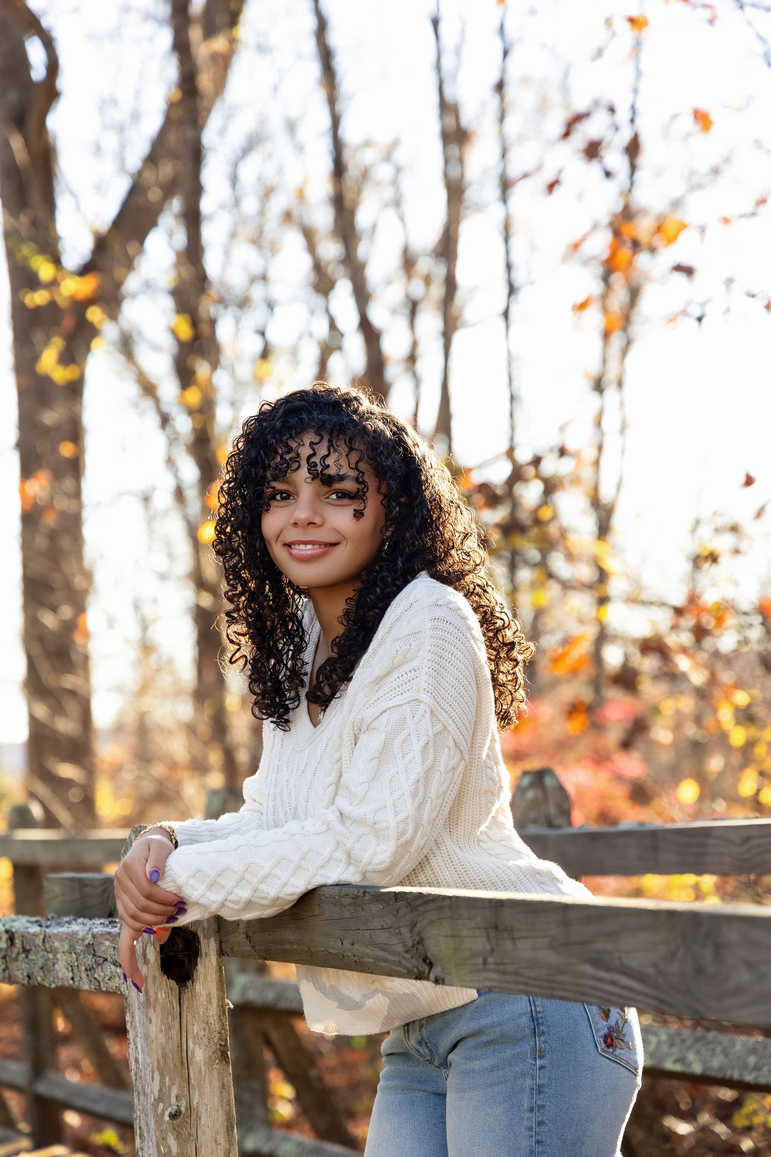 Fall photography session with rustic wooden fence and autumn foliage.