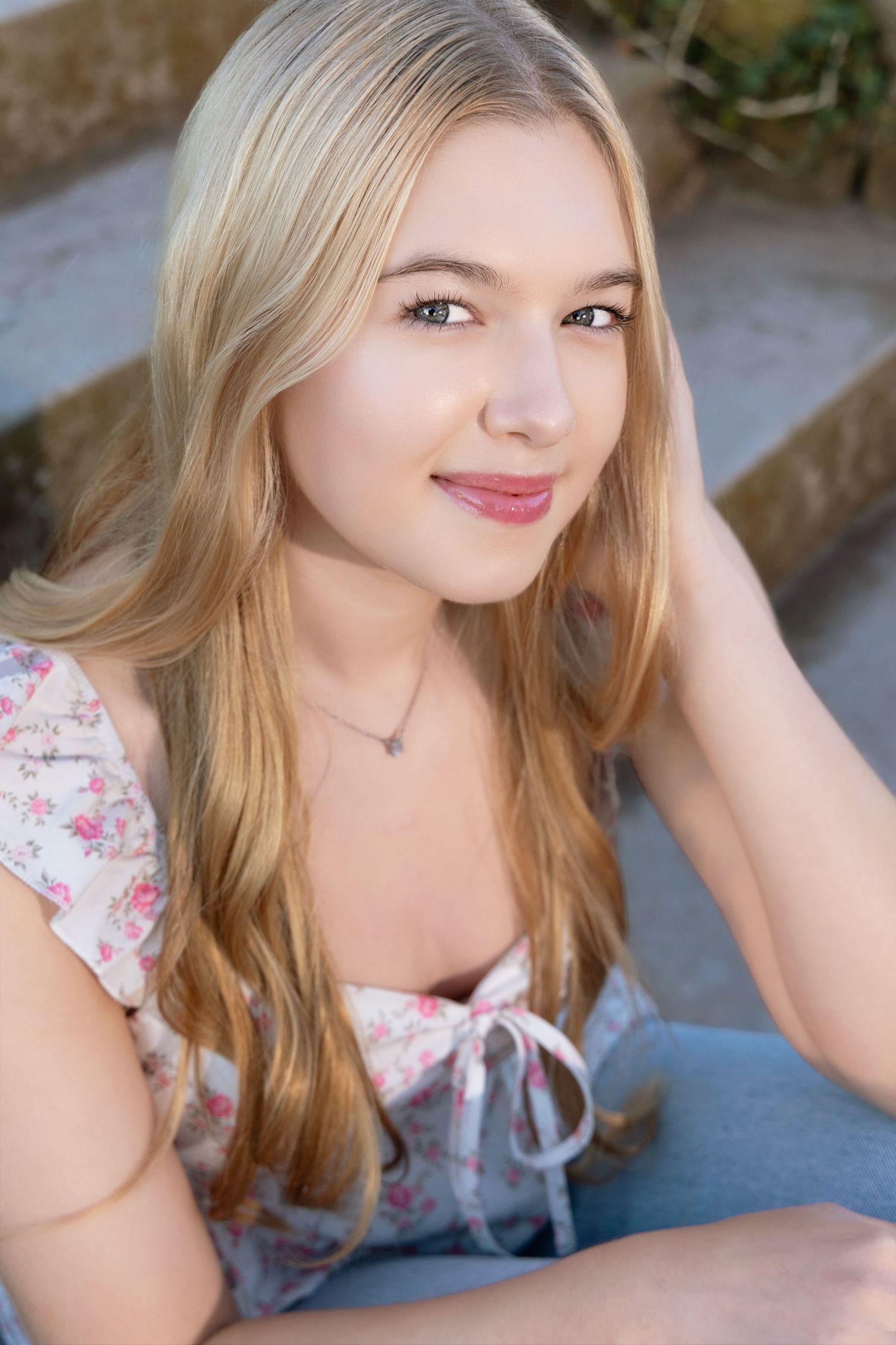Close-up portrait with soft lighting wearing floral top and natural makeup.