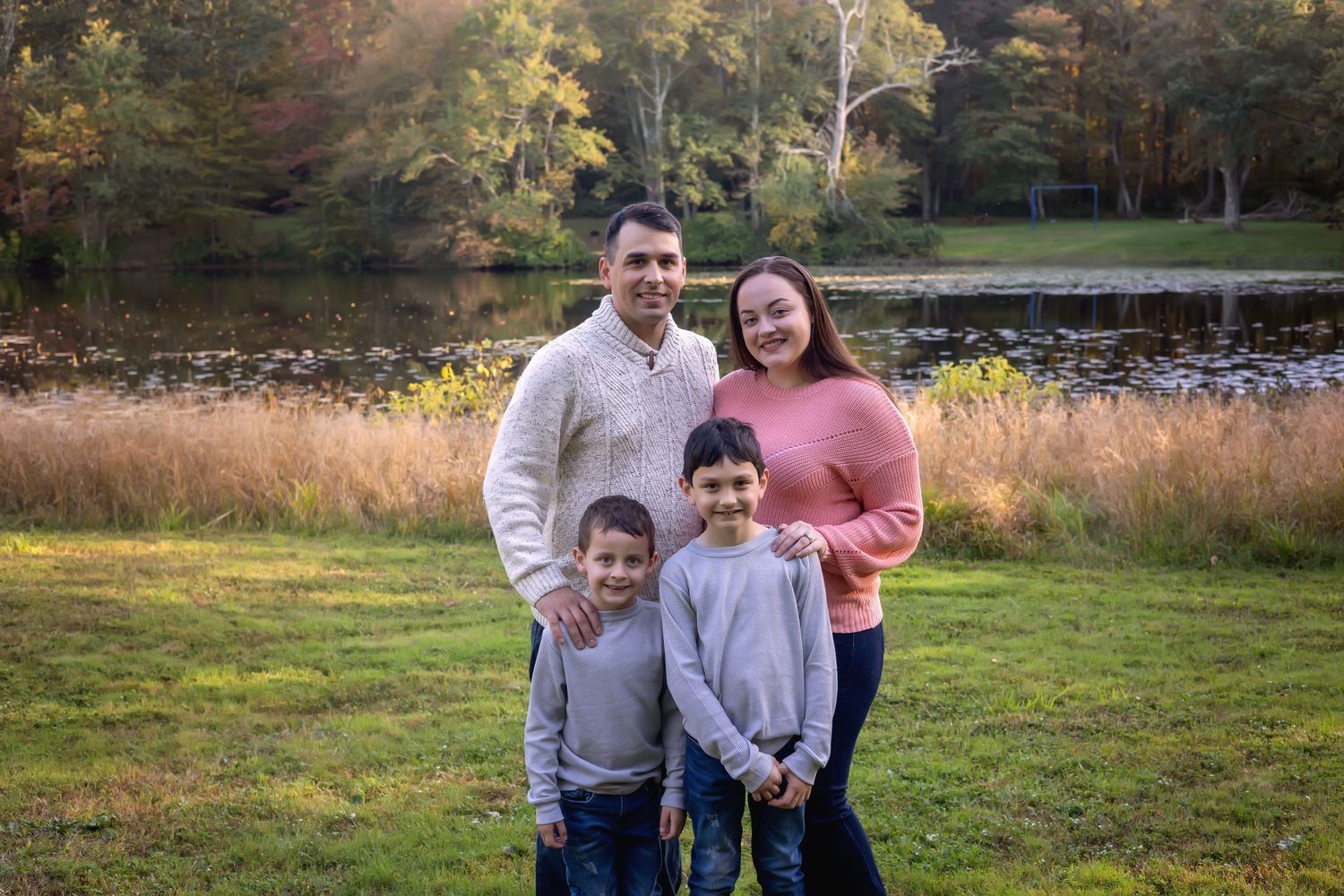 A group enjoying a casual outdoor photoshoot together in a scenic autumn field at sunset.
