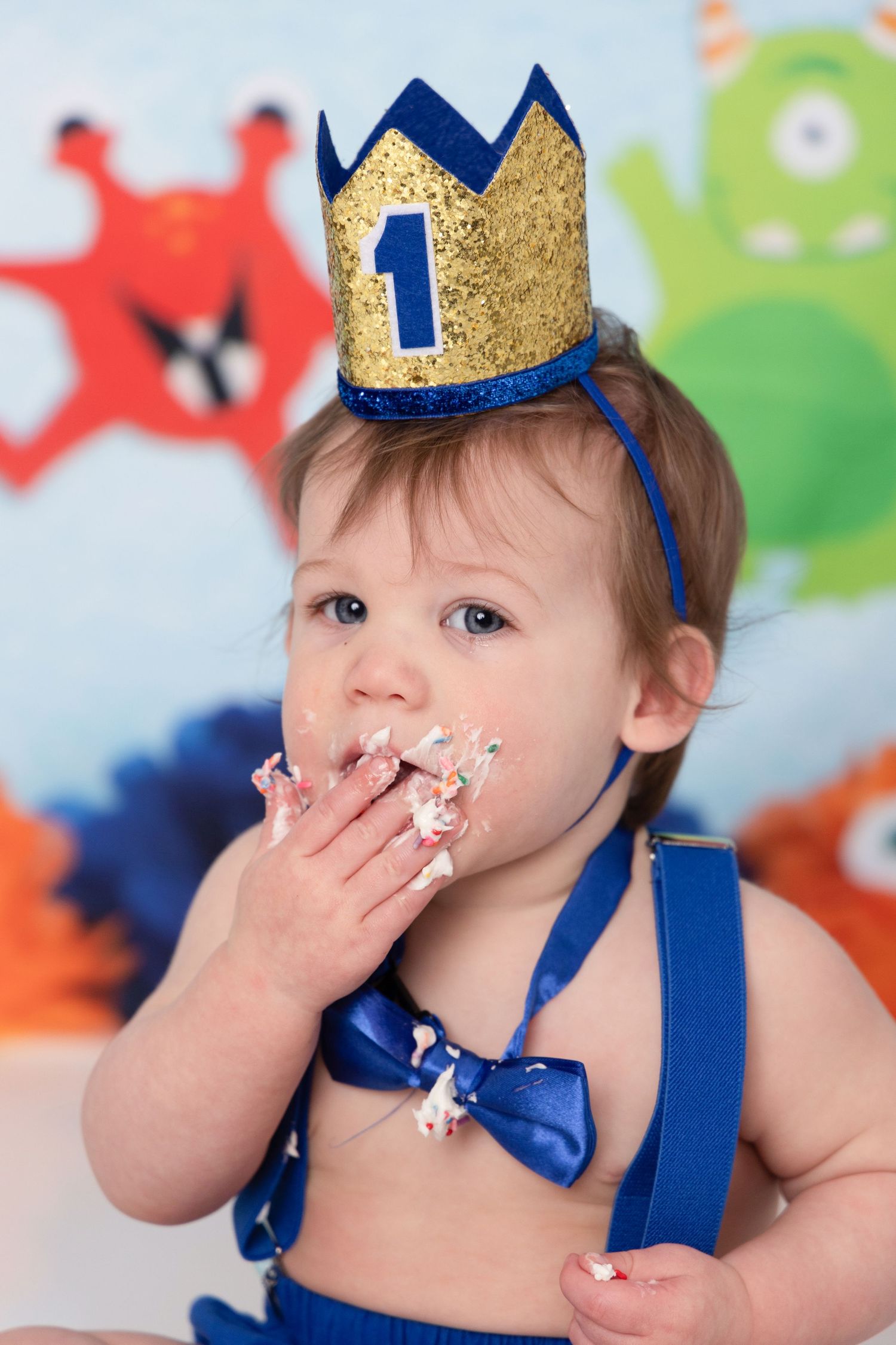 A first birthday cake smash photo sequence showing a baby in blue crown and outfit enjoying frosting covered cake.