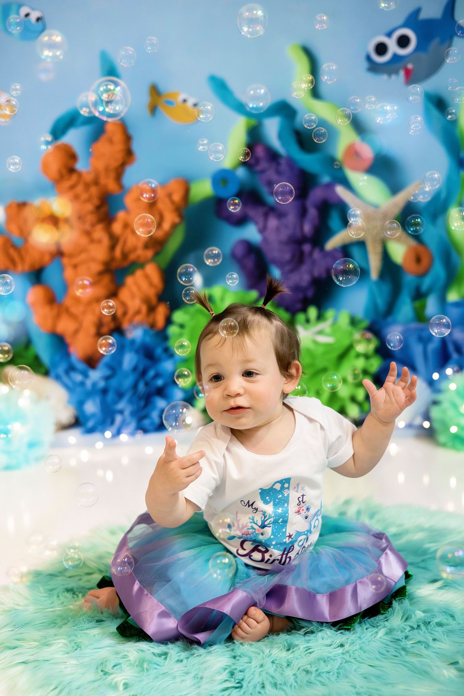 Whimsical underwater-themed photo setup with colorful sea creatures, bubbles, and teal backdrop for a special portrait session.