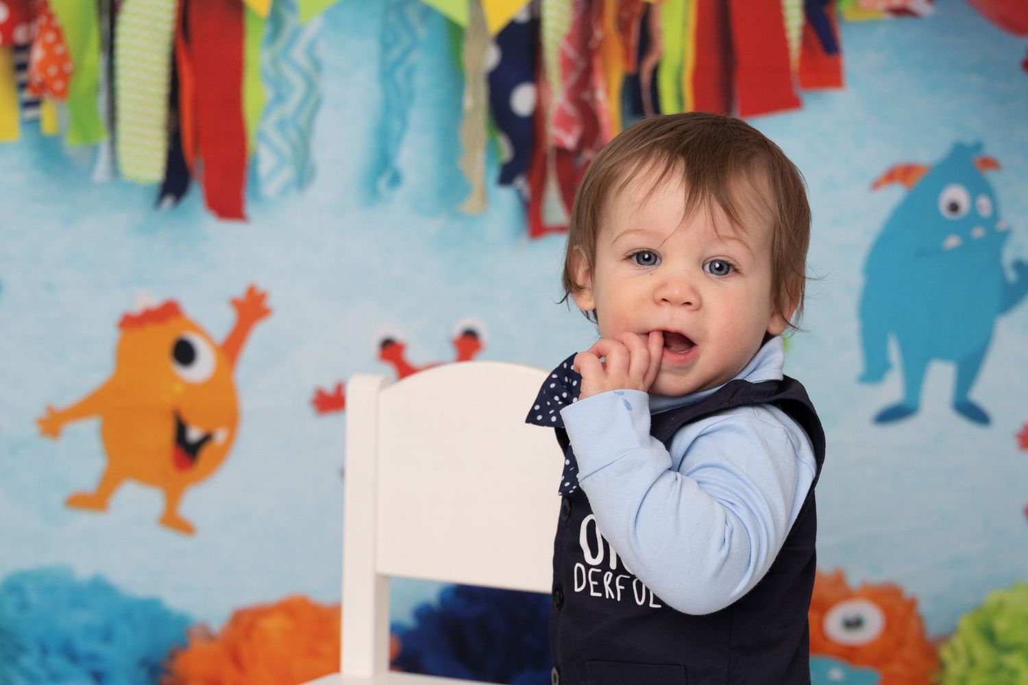 A child plays and laughs in front of a colorful wall mural decorated with cartoon monster characters.