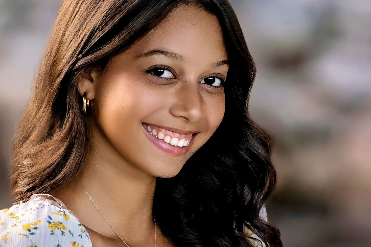 Portrait showing a bright smile against a soft blurred background.