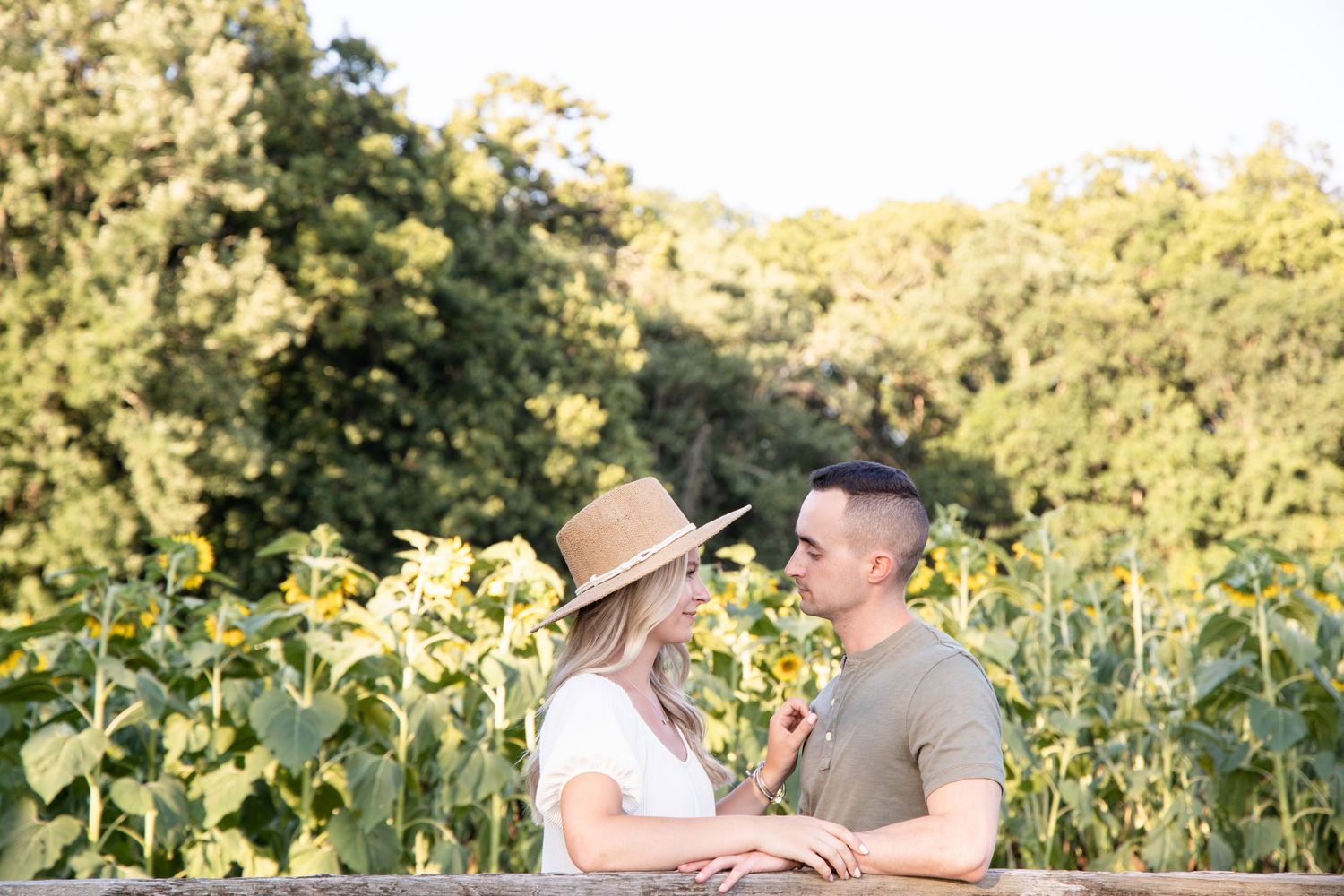 A couple shares tender moments in a golden sunflower field during a romantic sunset photoshoot.