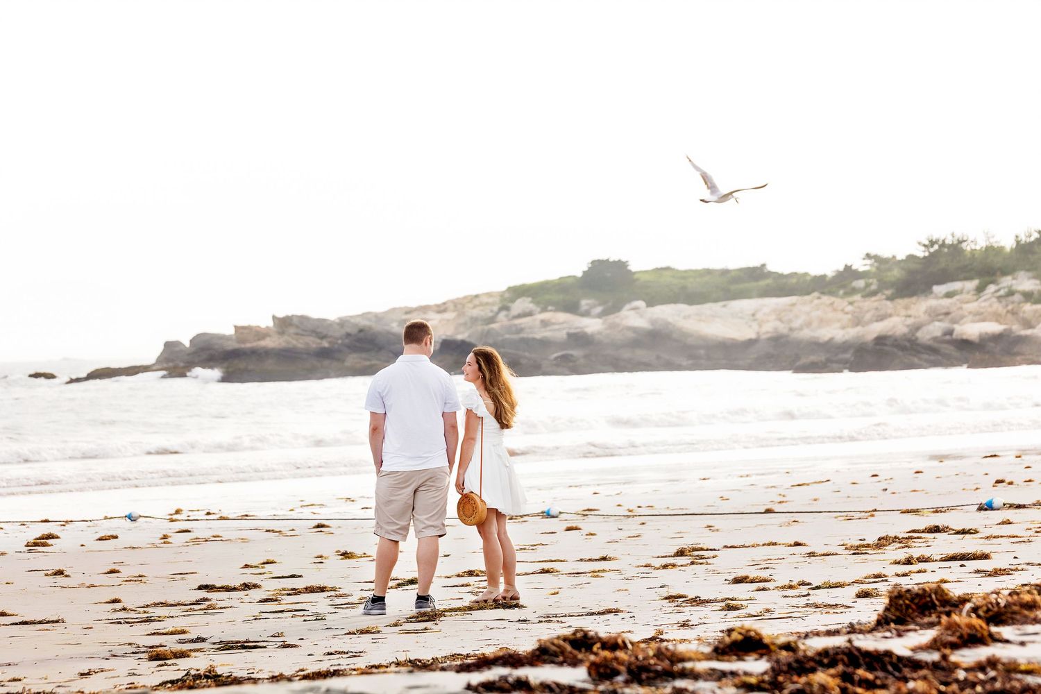 Couple walking together on a scenic beach at sunset with waves crashing on the shore.