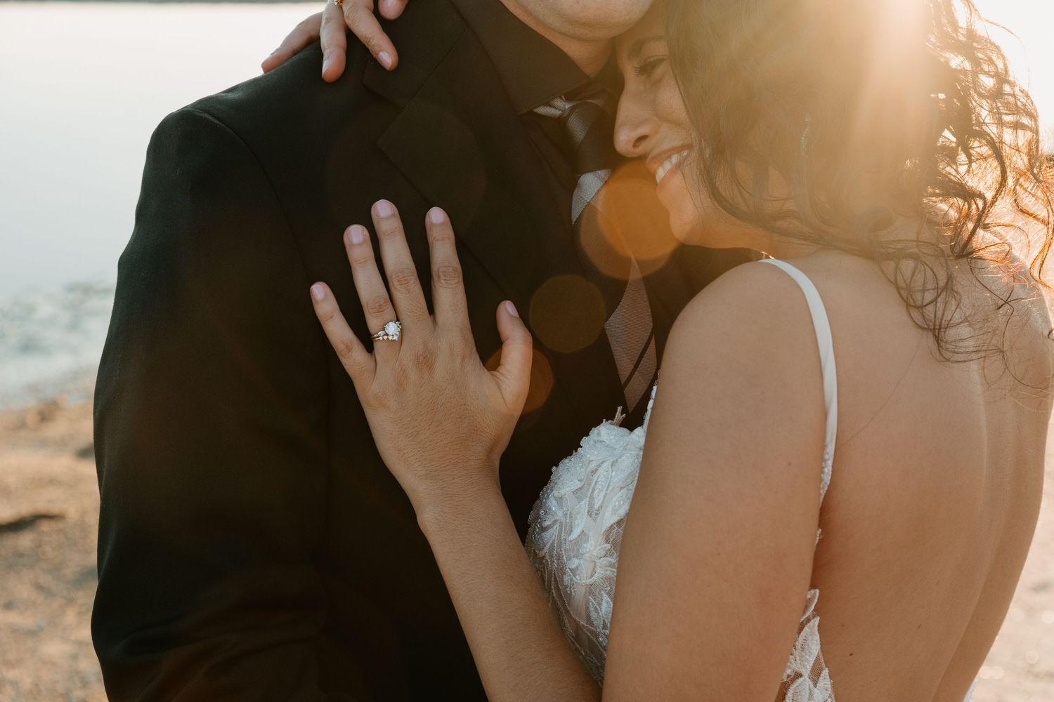 A romantic sunset moment between newlyweds as they embrace on a cliff with golden light.