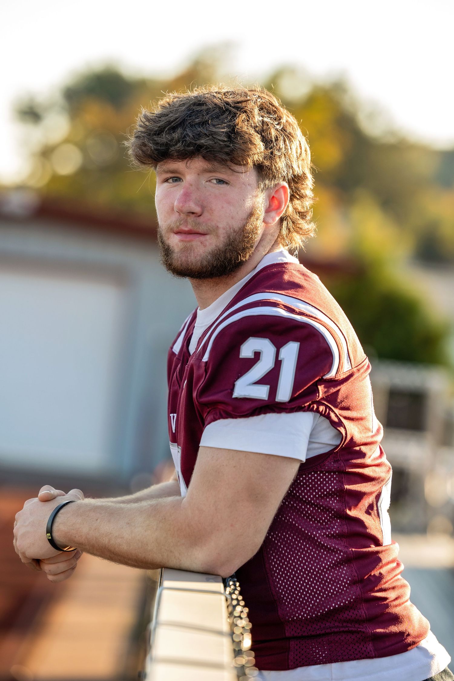 Football player in maroon jersey number 21 poses for athletic portraits.