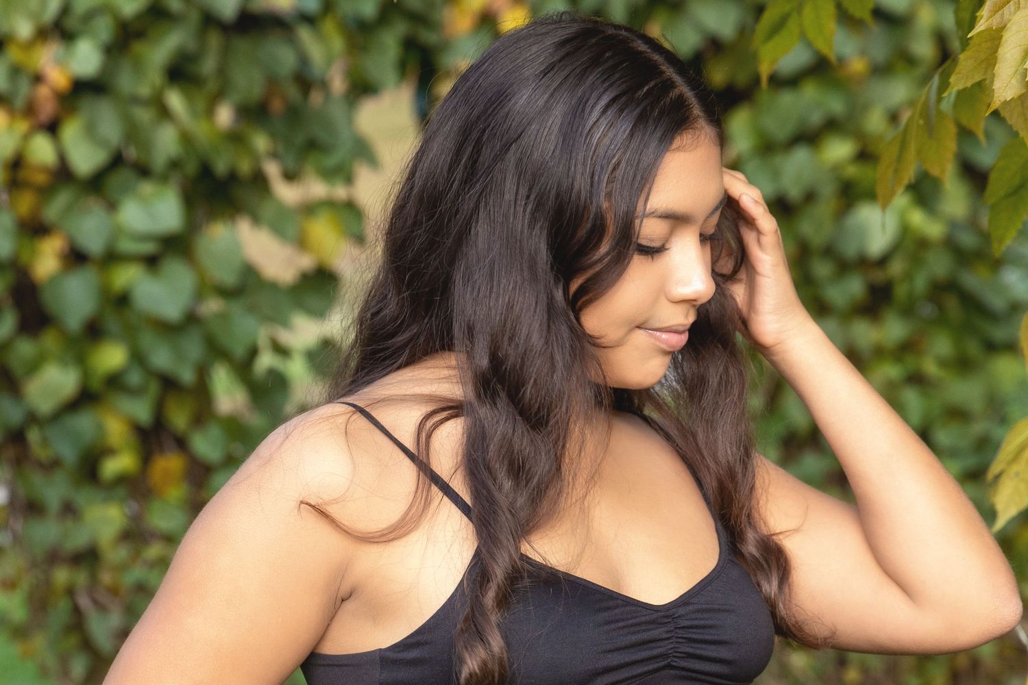 Woman in black tank top poses outdoors against green leafy background in series of candid shots.