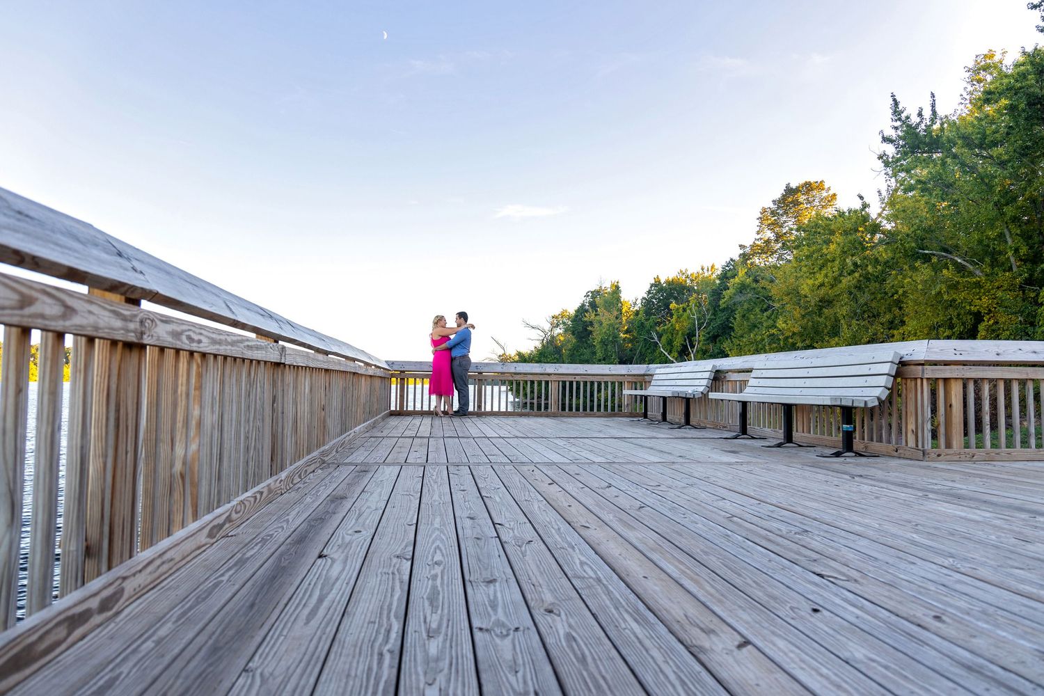 Long wooden boardwalk extends into the distance with railings on both sides and trees visible in the background.