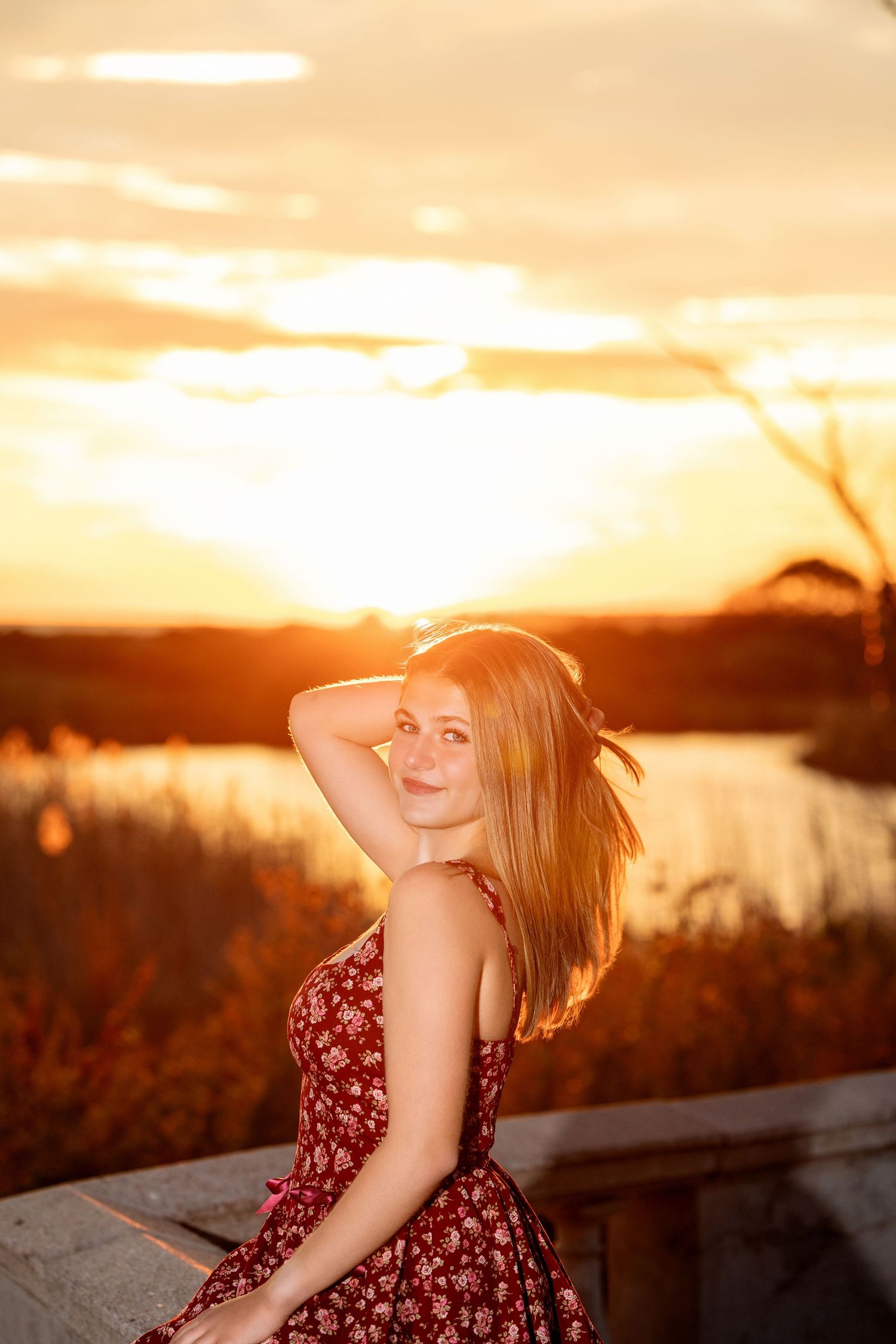 A floral dress silhouette against a vibrant sunset sky with golden light streaming through trees.