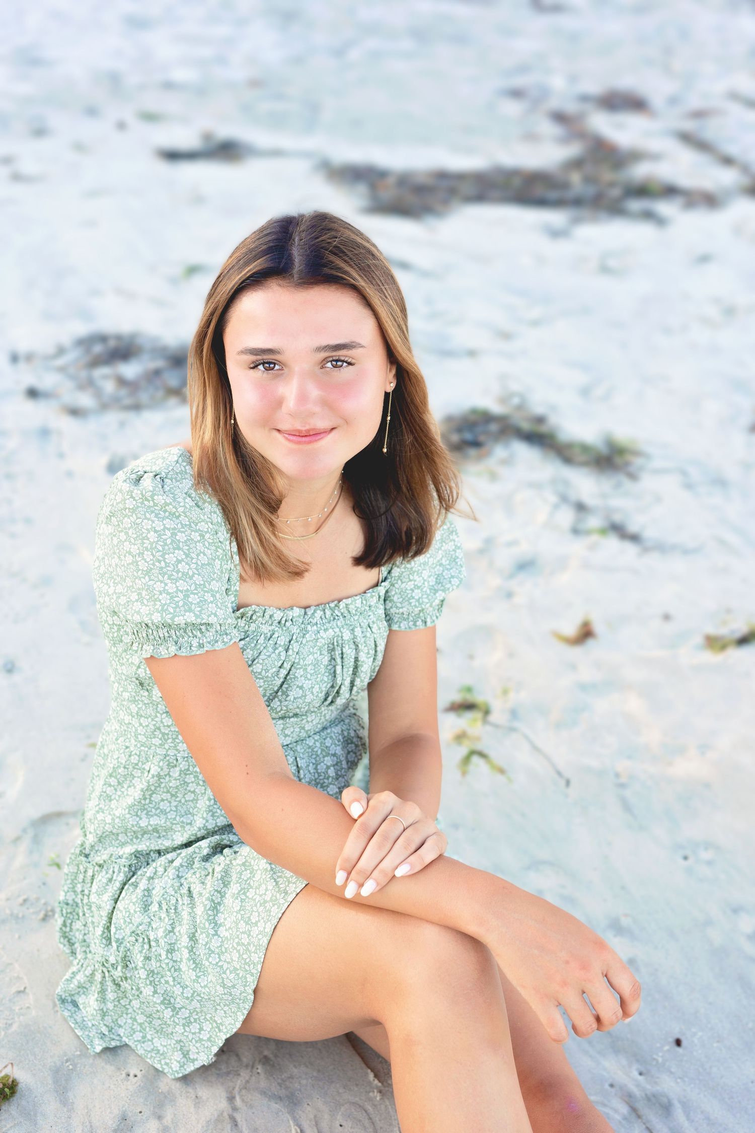 Person in mint green dress poses on white sandy beach during outdoor portrait session.