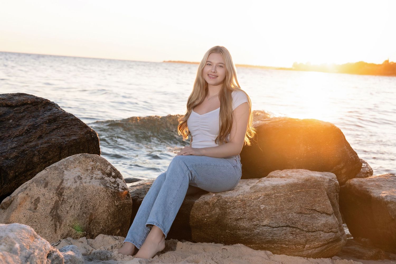 Sunset beach portrait on rocky outcrop with ocean waves in background.
