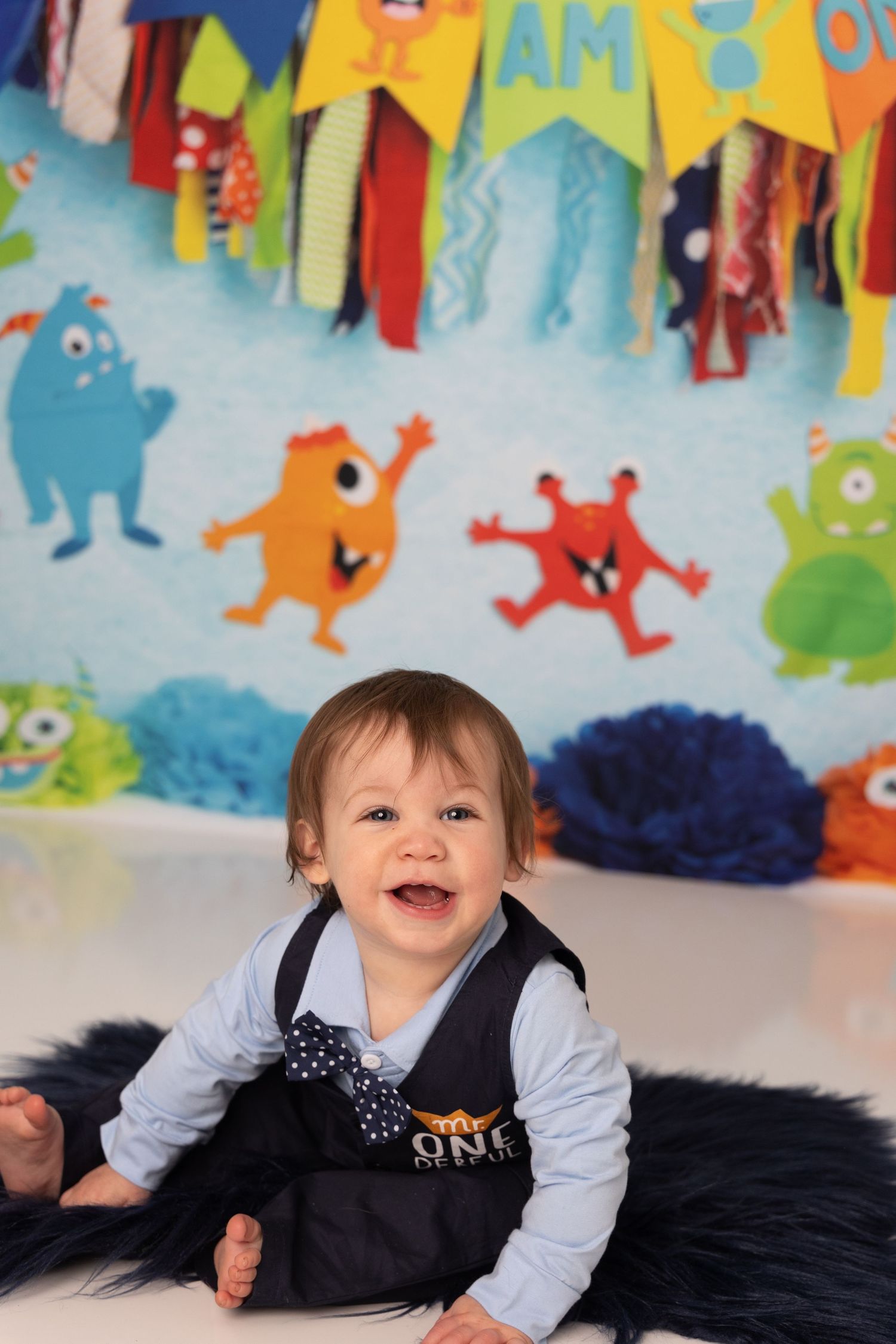 Colorful monster-themed birthday party backdrop with festive decorations and black furry rug.
