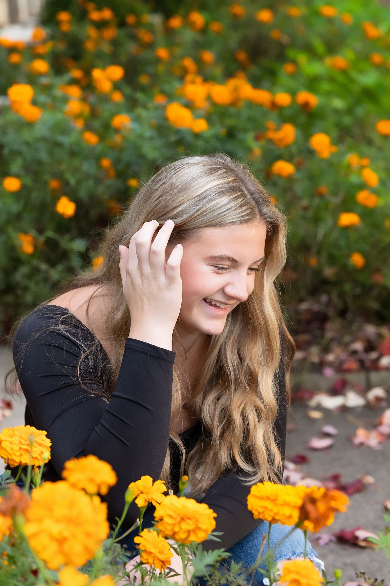Joyful candid moment captured in a garden filled with vibrant orange marigold flowers on a sunny day.