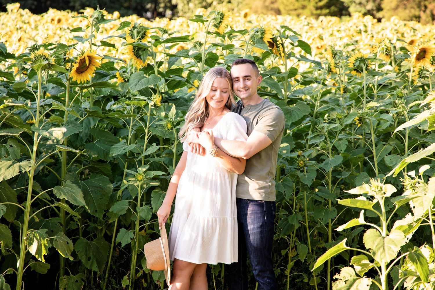 A couple shares a tender moment among tall sunflowers in a garden setting during golden hour.