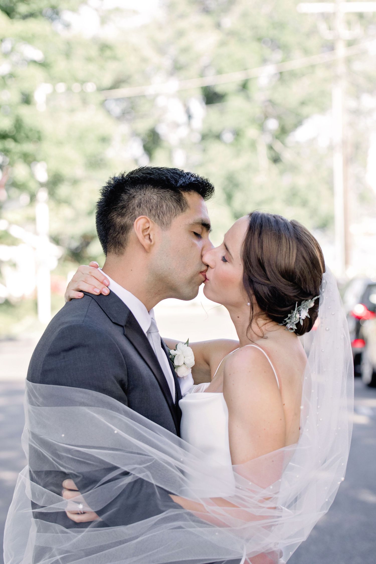 A romantic wedding couple shares a tender kiss under a flowing white veil in a series of connected photos.
