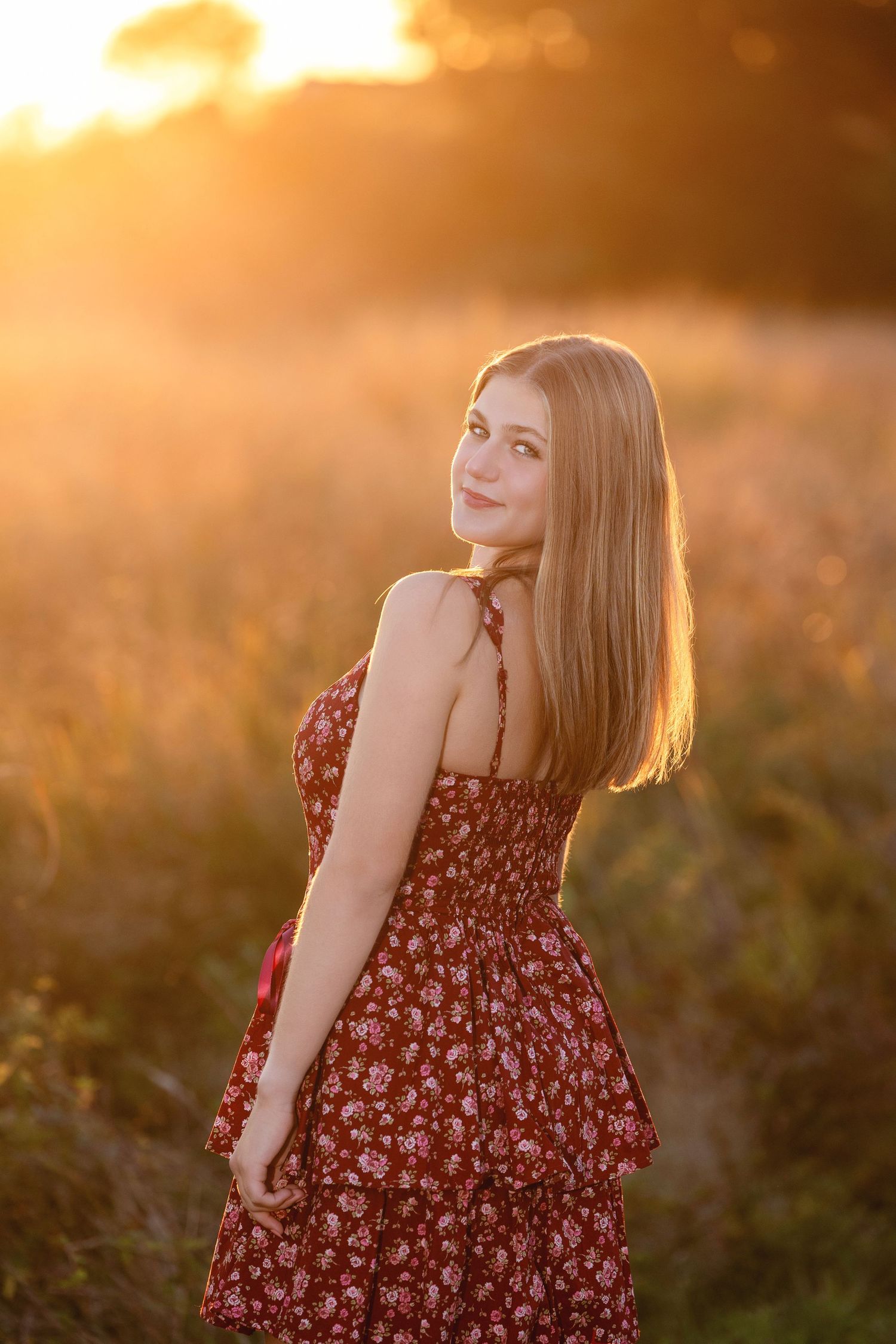 Person wearing burgundy floral dress twirls in warm evening sunlight.