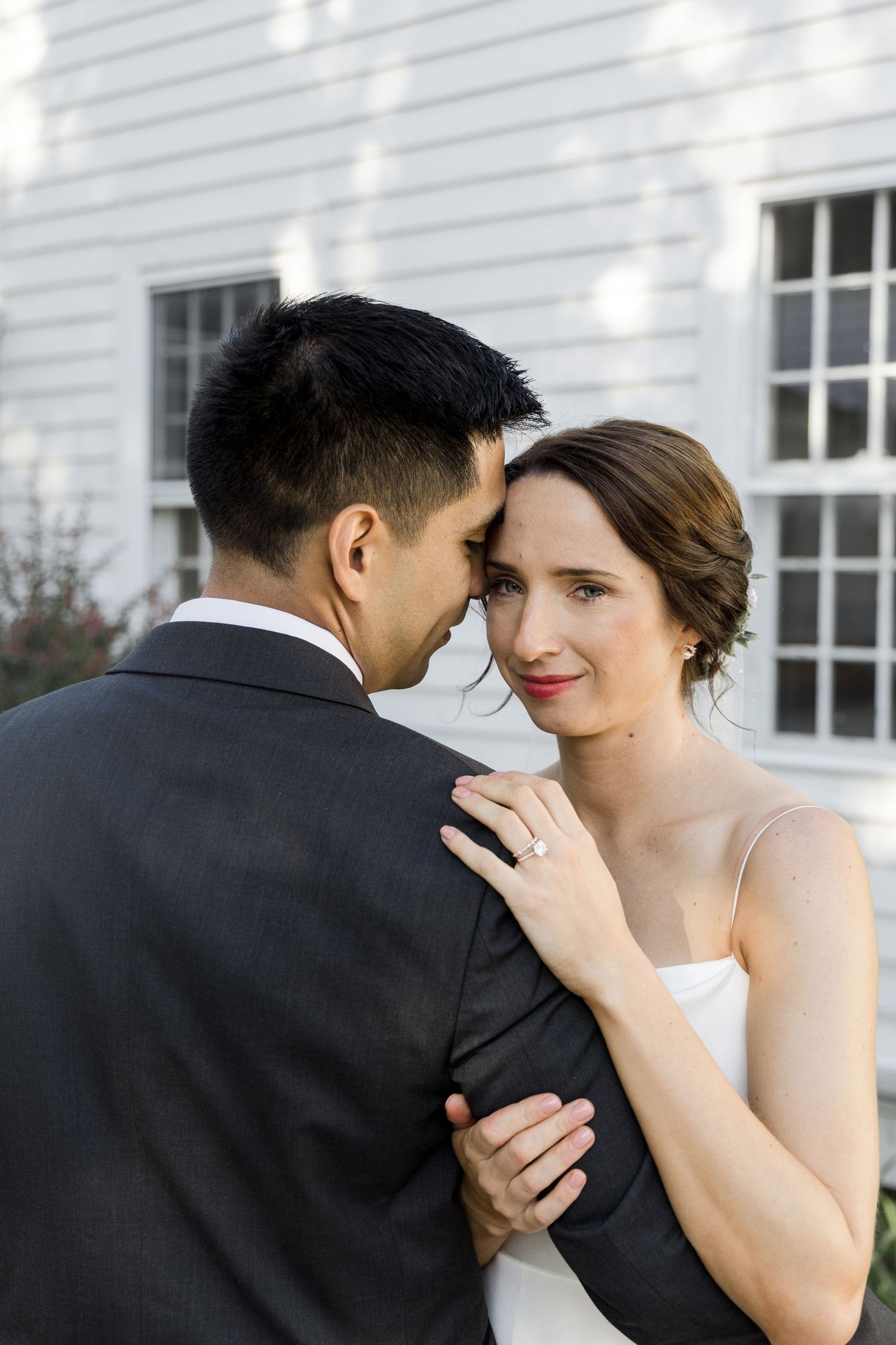 A romantic wedding couple shares an intimate moment together in a series of close-up portraits against a white wall.