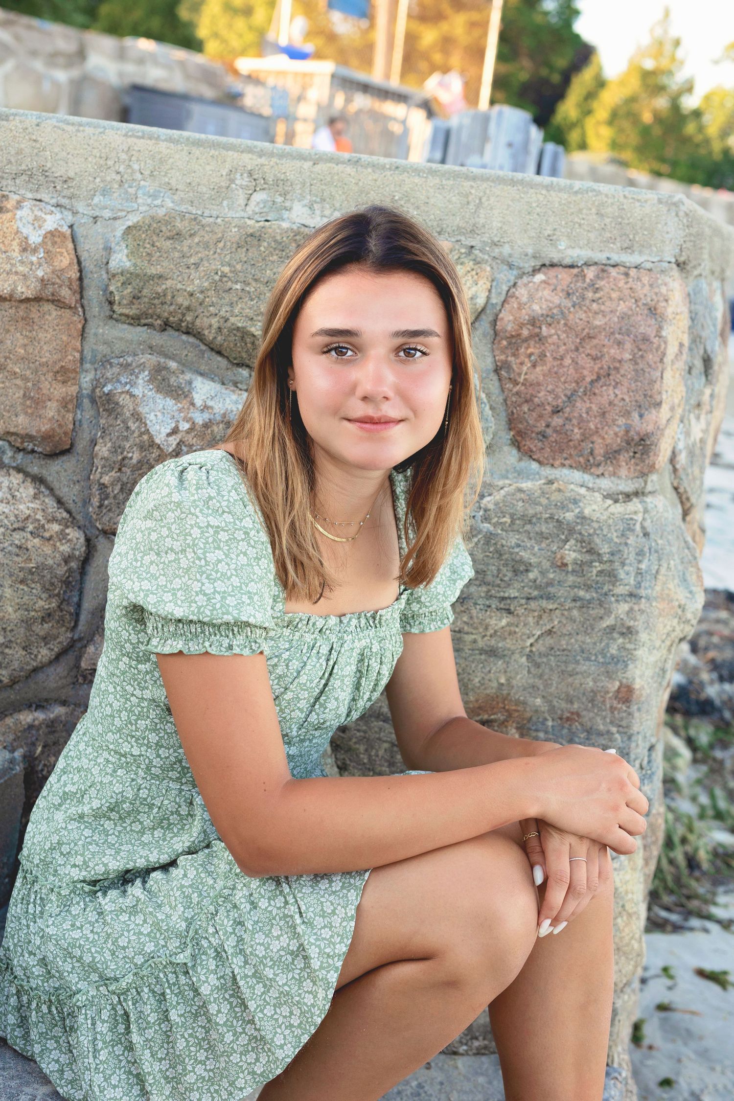A series of outdoor portrait photos featuring someone in a light green floral dress sitting on stone steps.
