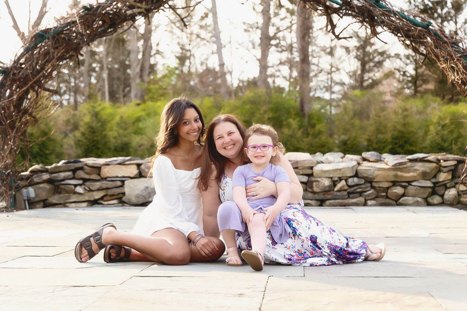 Family relaxes together on sandy beach during golden hour sunset photoshoot.
