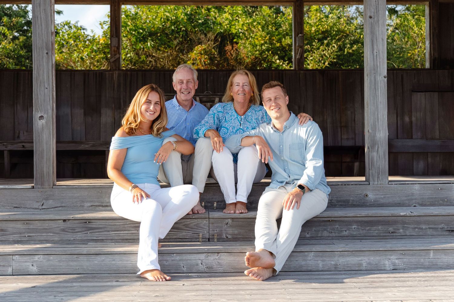 A panoramic sequence showing people in white clothing sitting and posing on outdoor wooden steps in natural lighting.