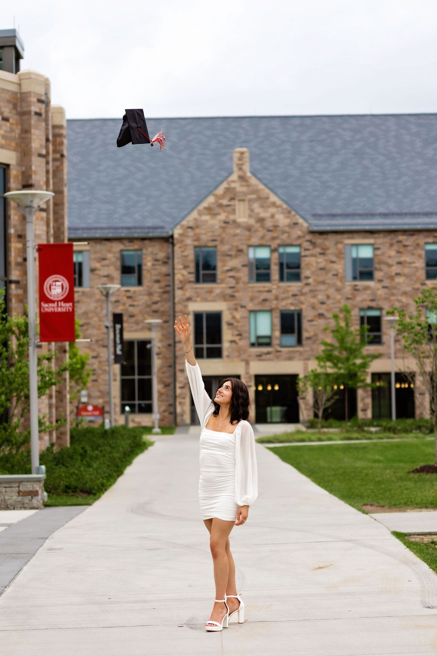 A person in white attire walks along a stone pathway in front of a traditional collegiate building complex.