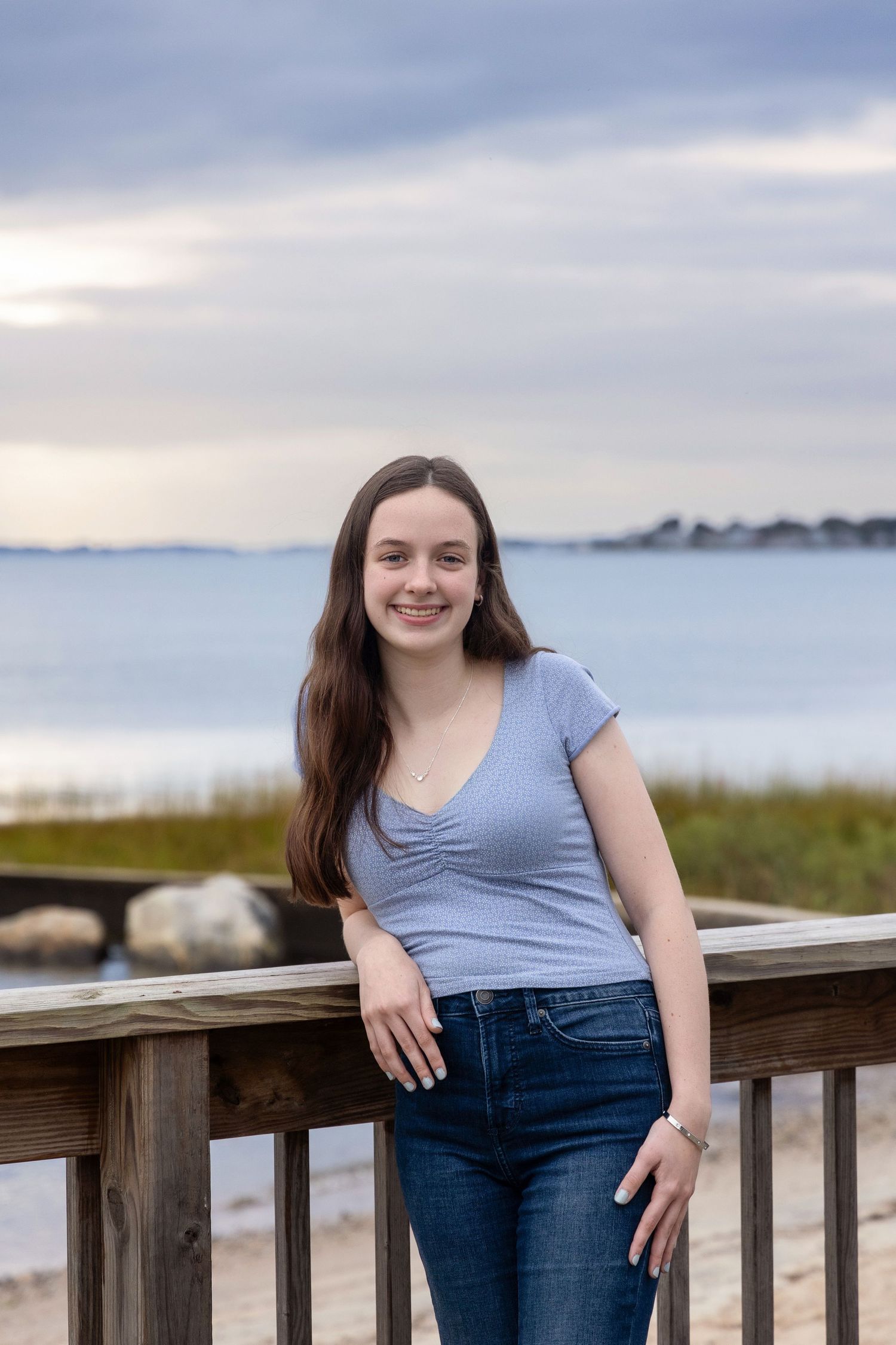 Casual waterfront portrait session on a wooden deck with coastal views.