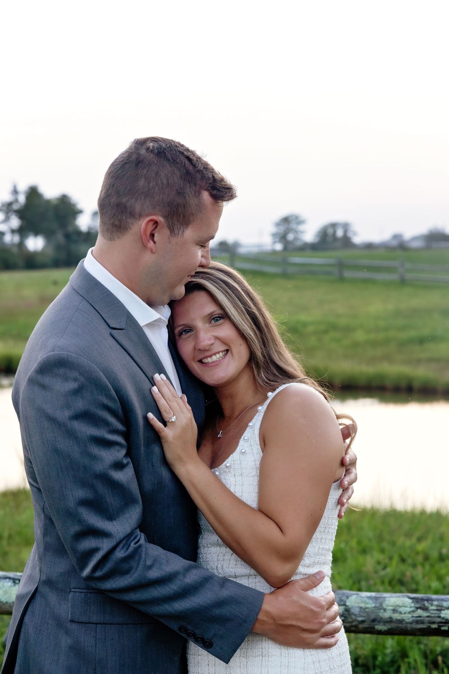 Newlyweds sharing tender moments against scenic rural landscape.
