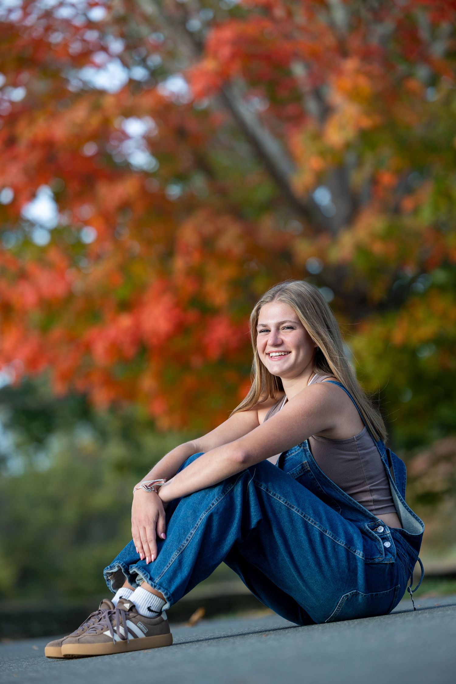 Fall senior portrait session with casual poses against vibrant autumn foliage.