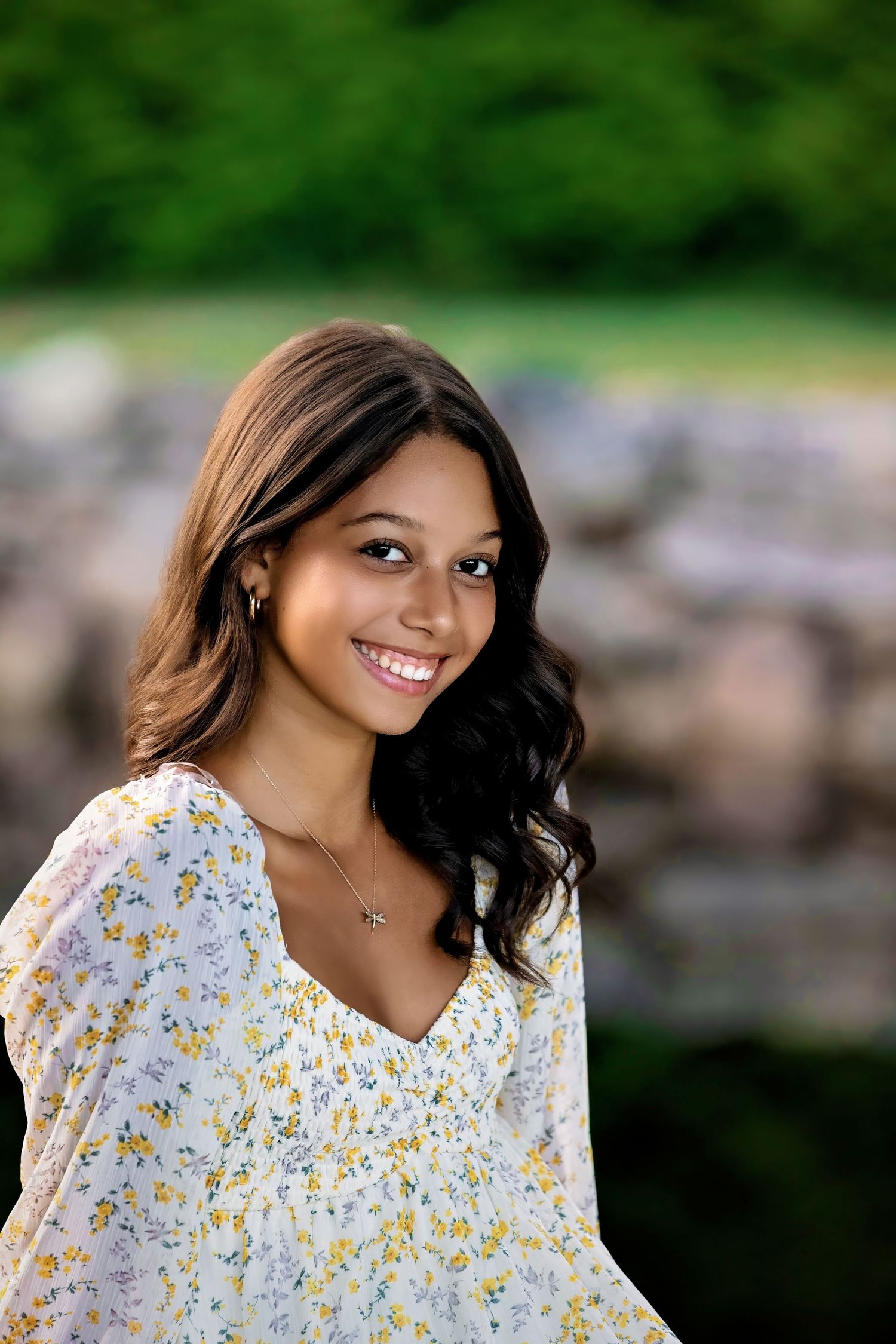 Portrait session with a white floral dress against a natural outdoor setting with rocks.