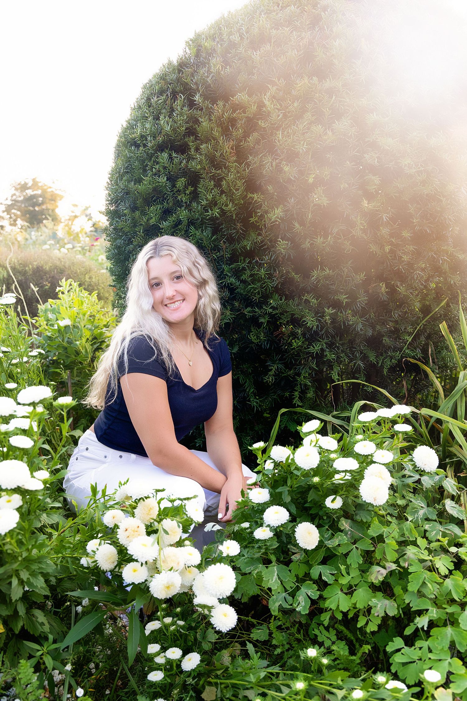 Outdoor portrait session among white blooming flowers with sunlit background.