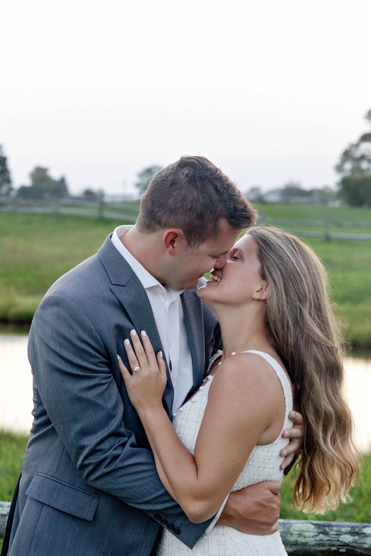 Wedding couple embracing in romantic outdoor setting by water.