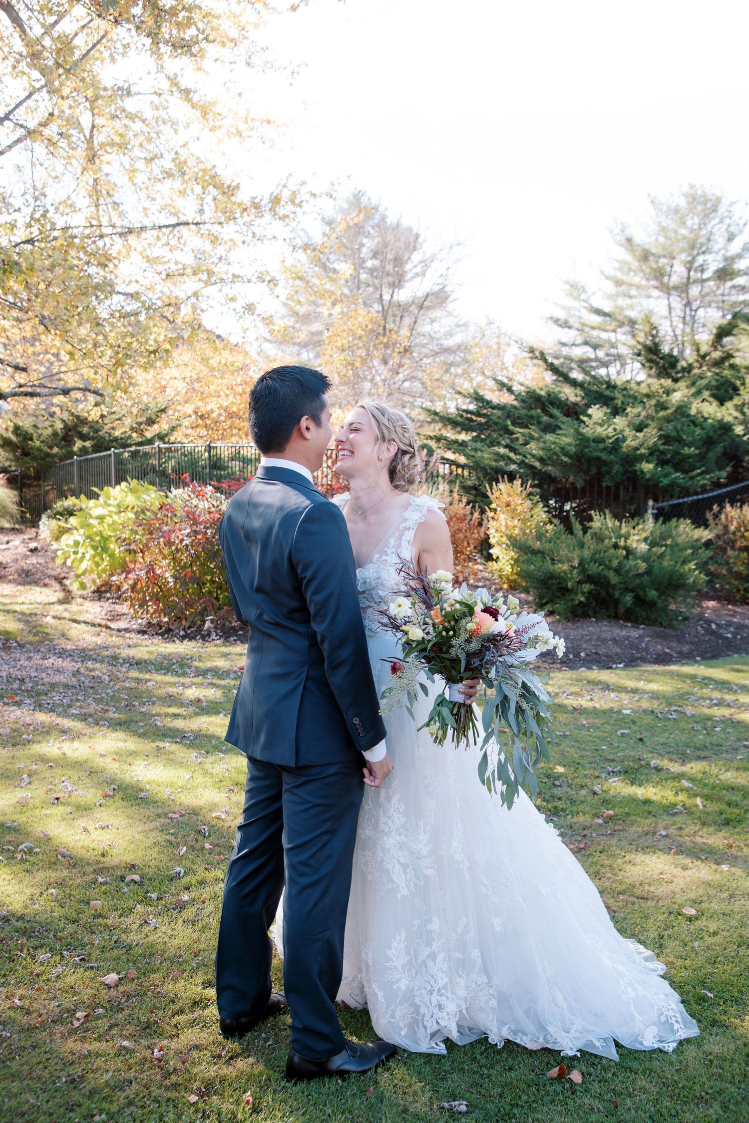 A couple shares an intimate moment together outdoors during an autumn wedding ceremony surrounded by evergreen trees.