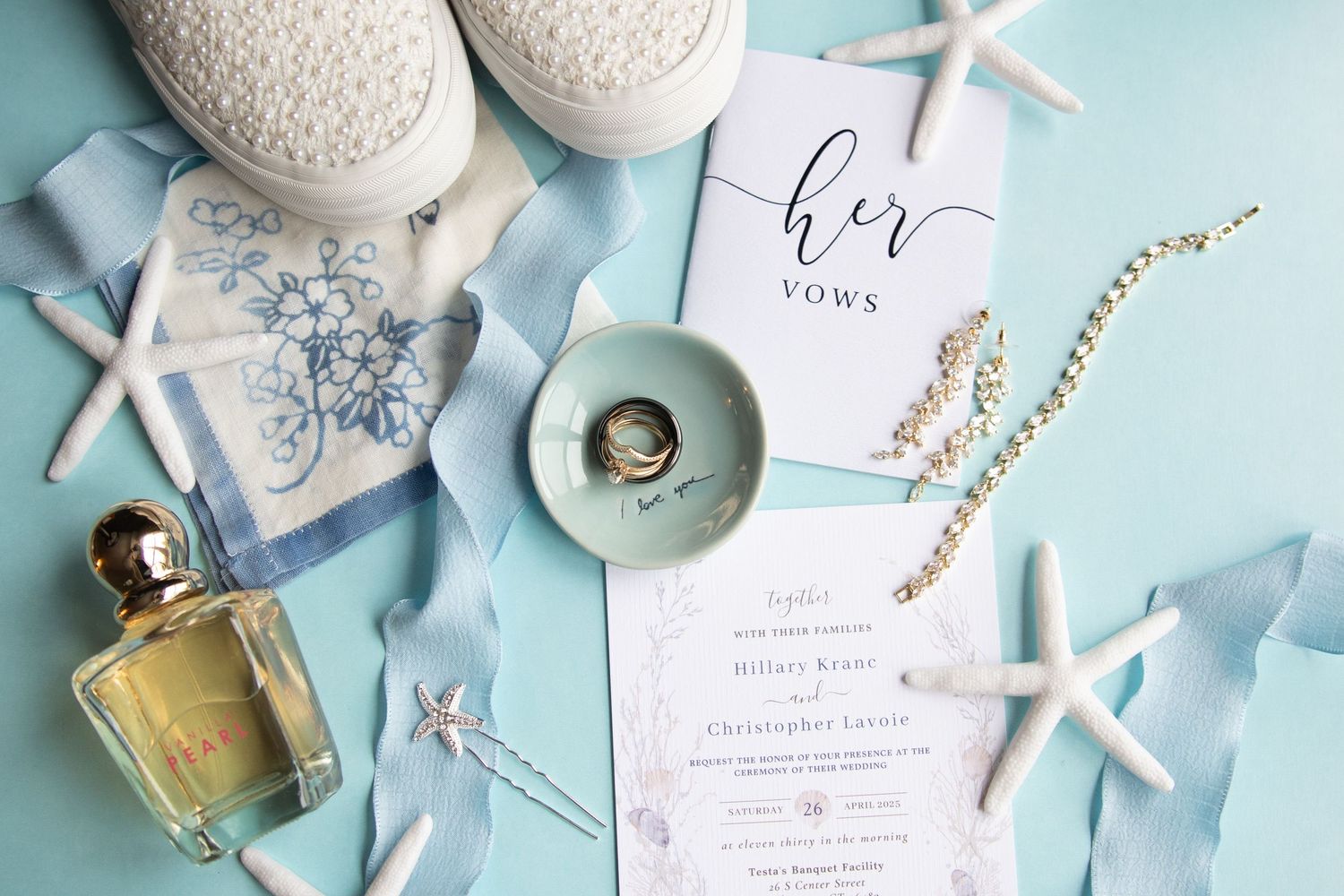 Beach themed wedding details with starfish, invitation and accessories on light blue background.