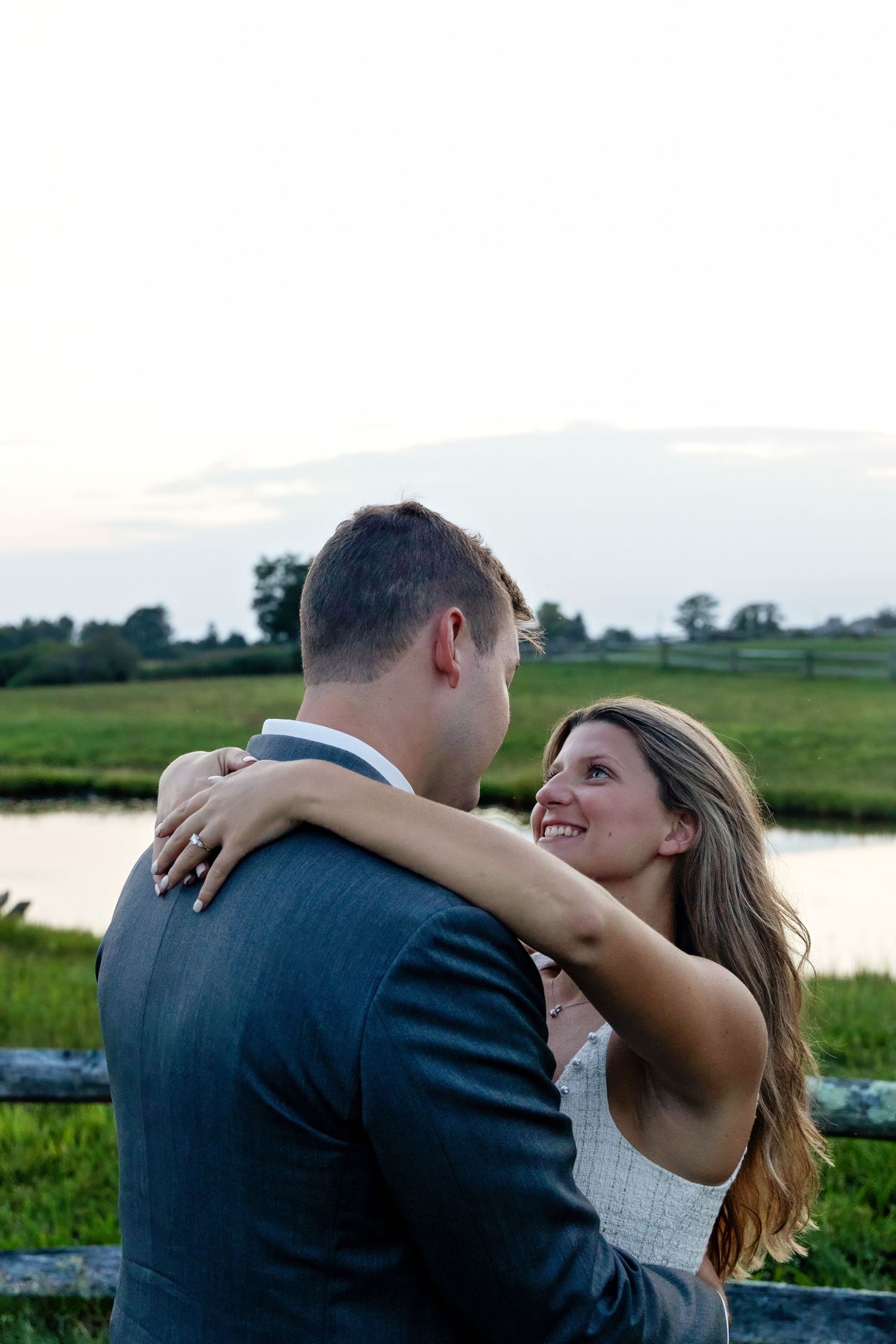 Romantic sunset photoshoot of couple by waterside landscape.