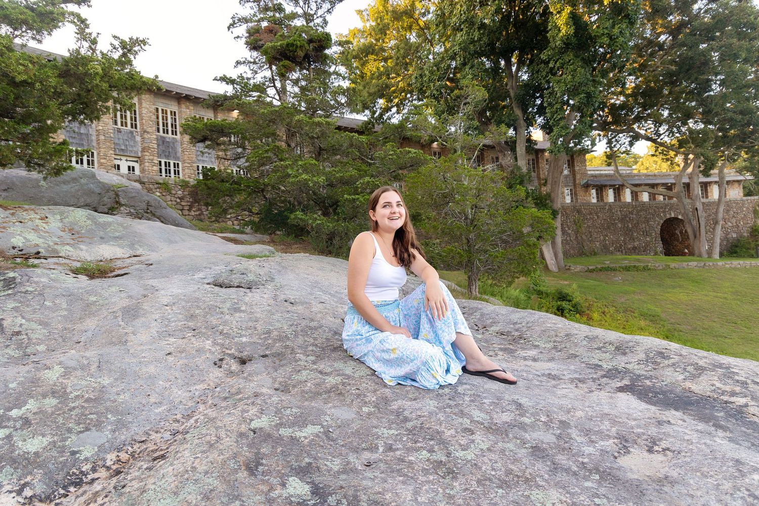 Seven scenic outdoor photos show someone sitting on large rocks surrounded by trees and buildings in a natural setting.