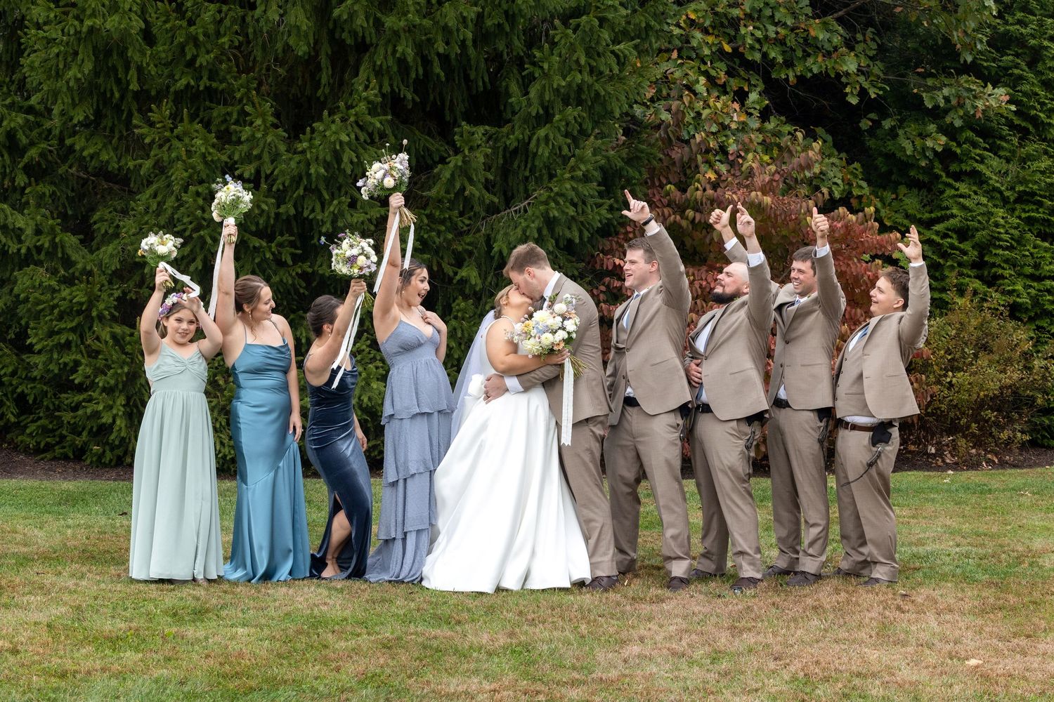Wedding party strikes fun pose with bridesmaids and groomsmen on opposite sides of couple.
