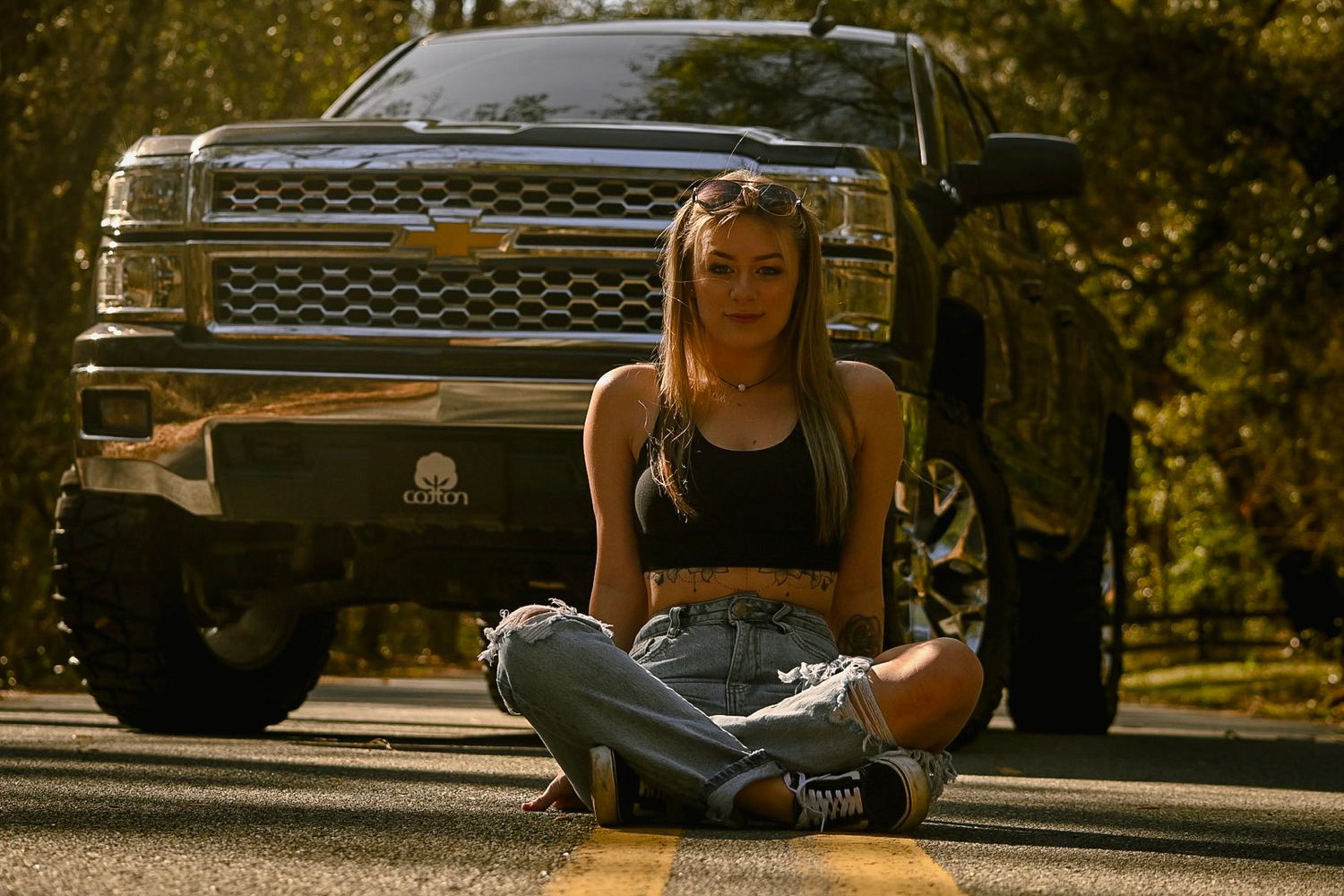 Person relaxing on steps near parked vehicles during golden hour.