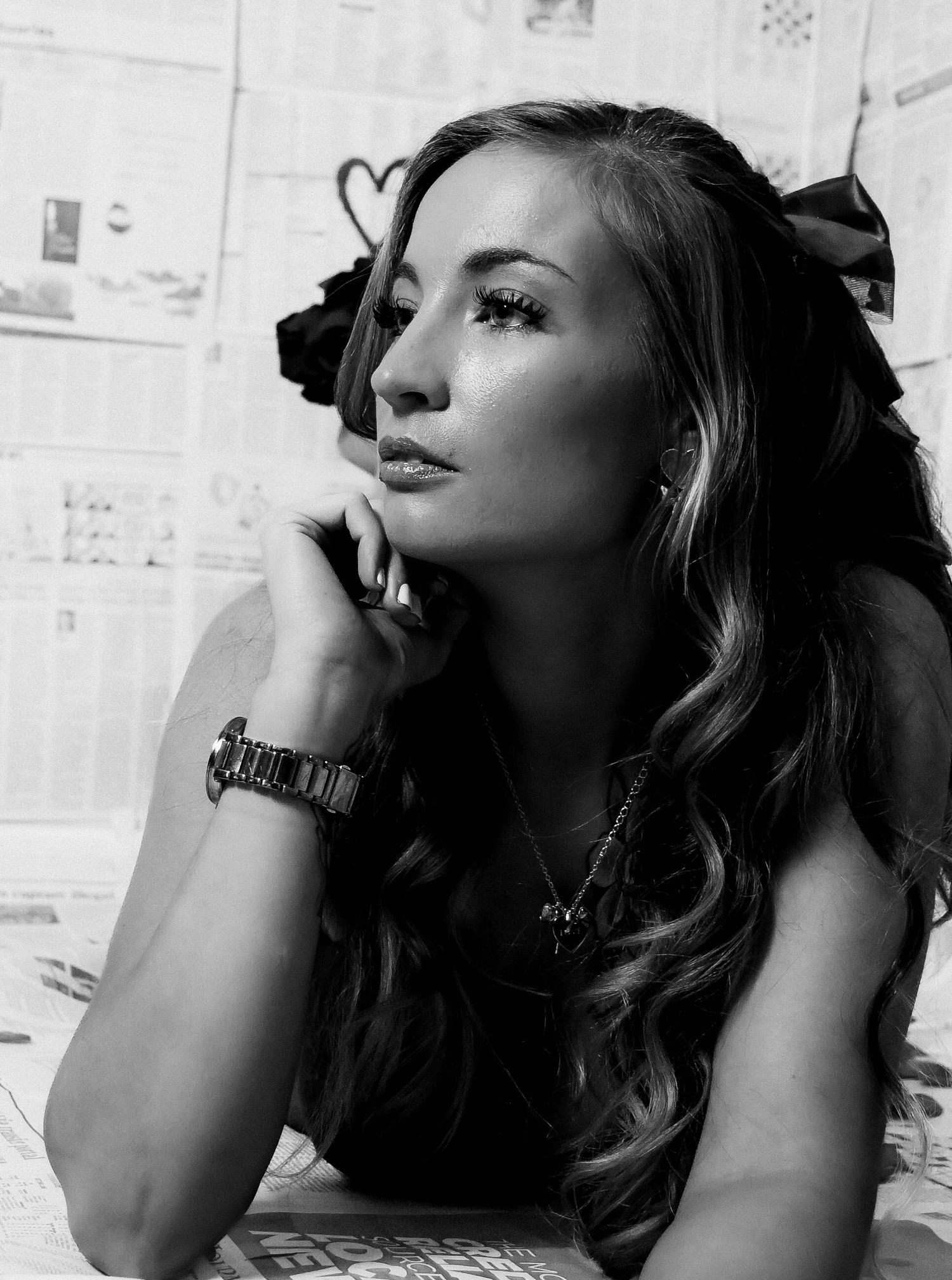 Black and white artistic portrait against newspaper wall background.