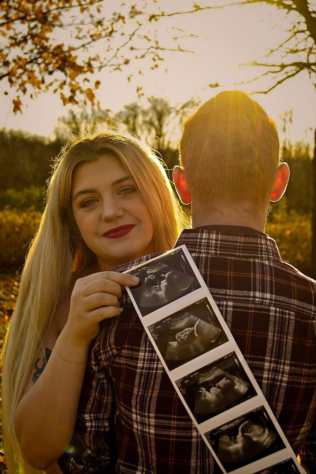 A couple holds ultrasound photos during a sunset maternity photoshoot.