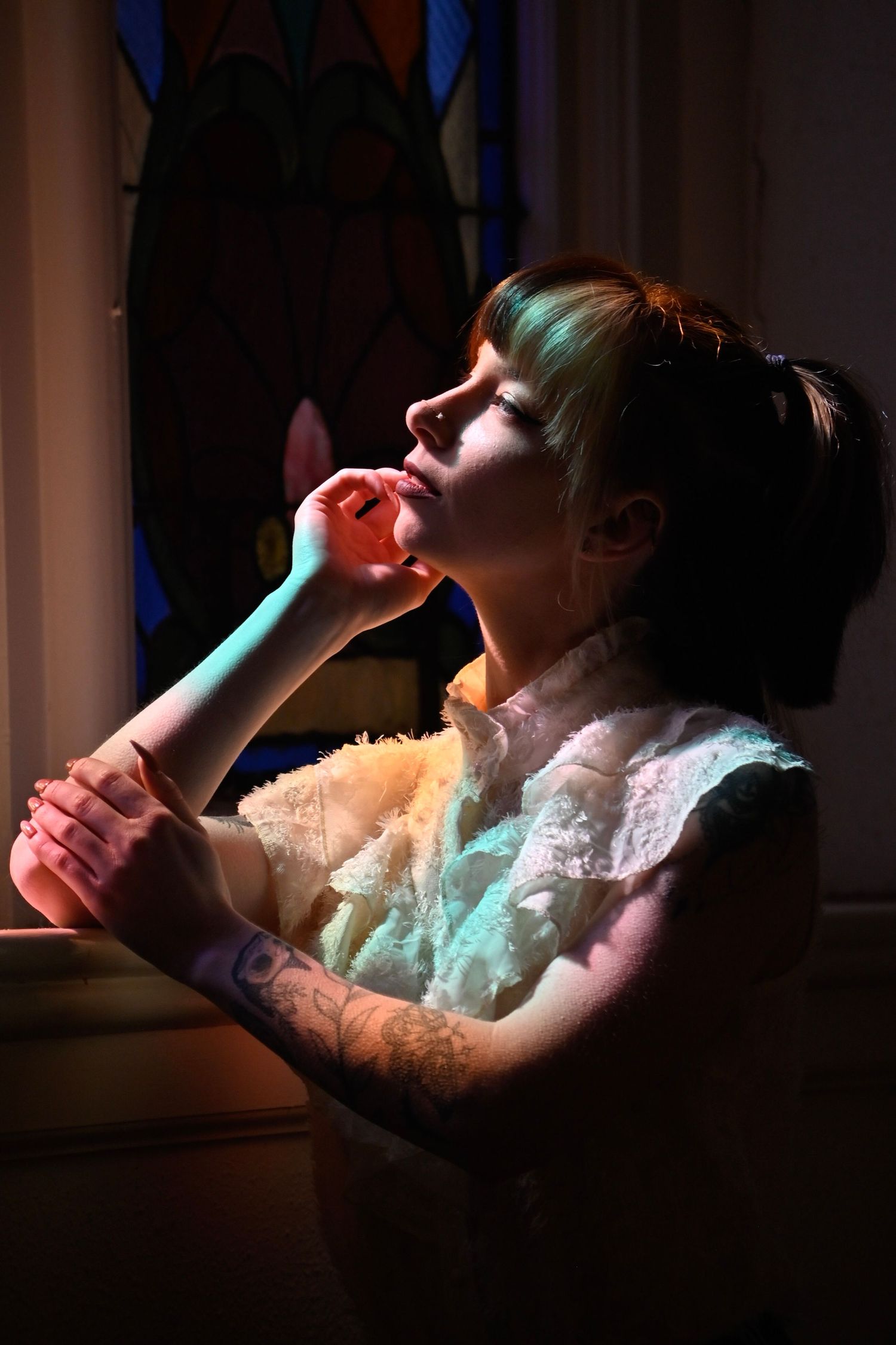 A series of dramatic side-lit photos showing someone reclining in a lace dress against dark shadows.