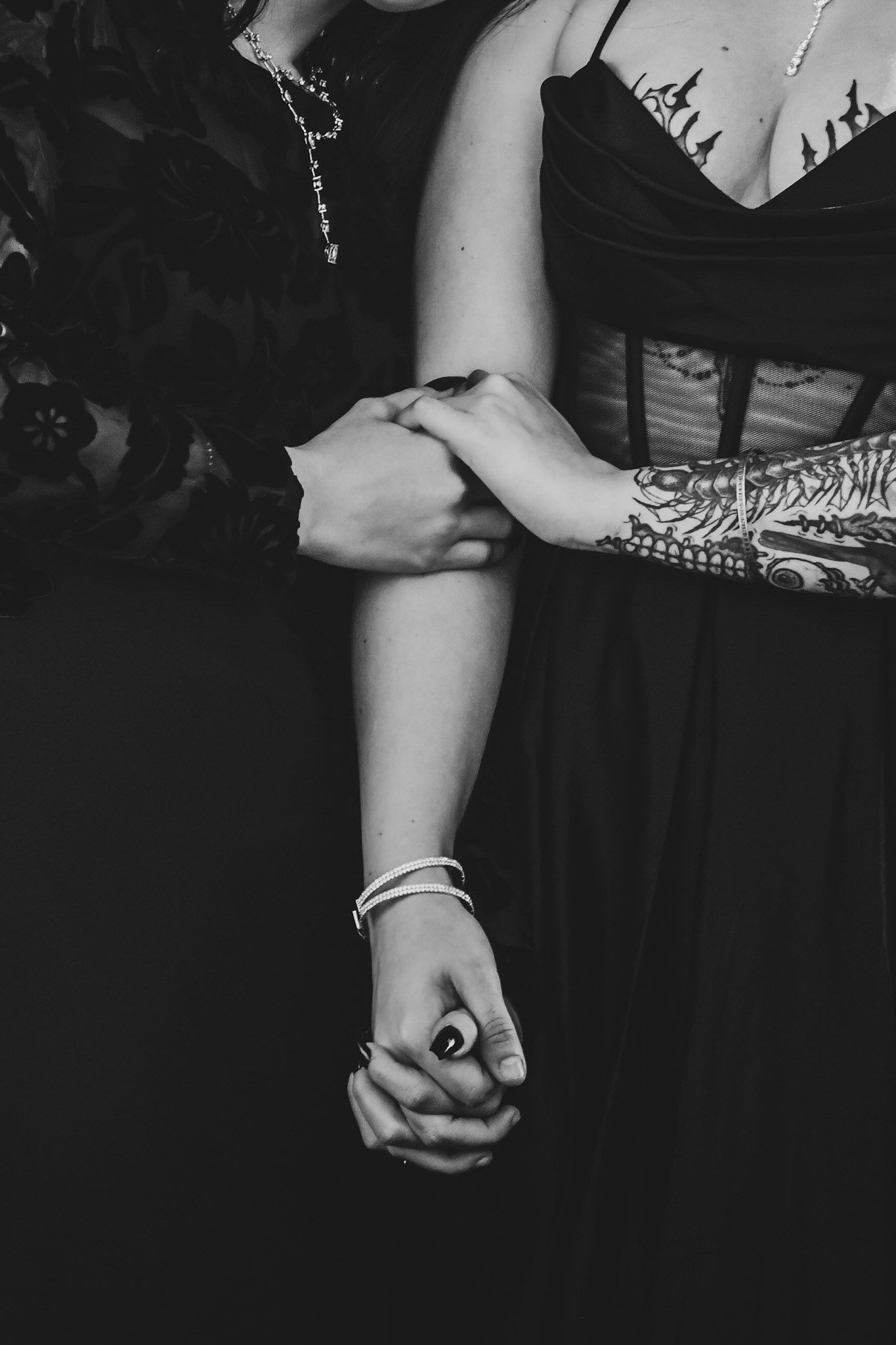 A black and white photo showing a close-up view of hands wearing rings against a dark background.