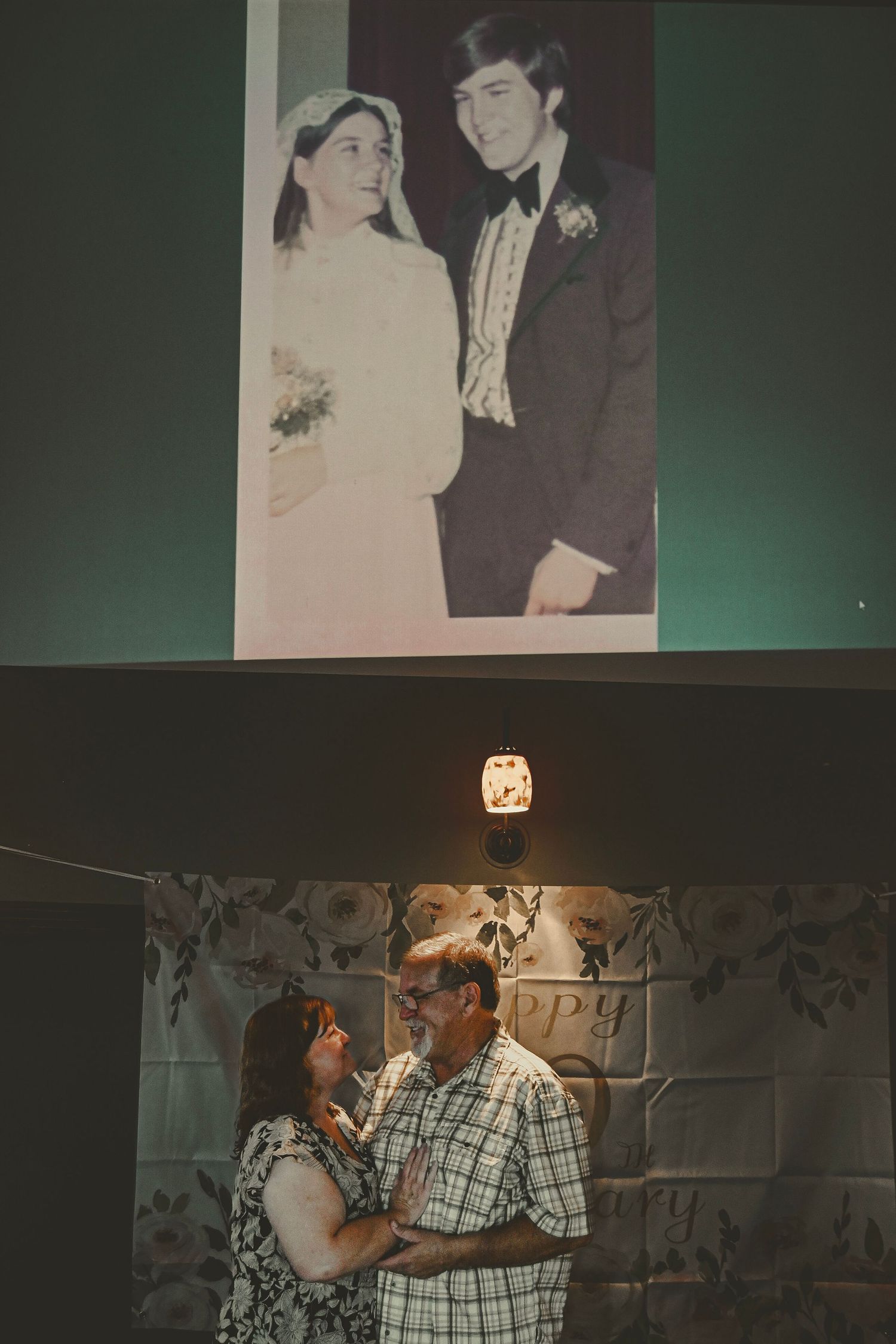Wedding photo displayed above a couple dancing in dim lighting at an event.