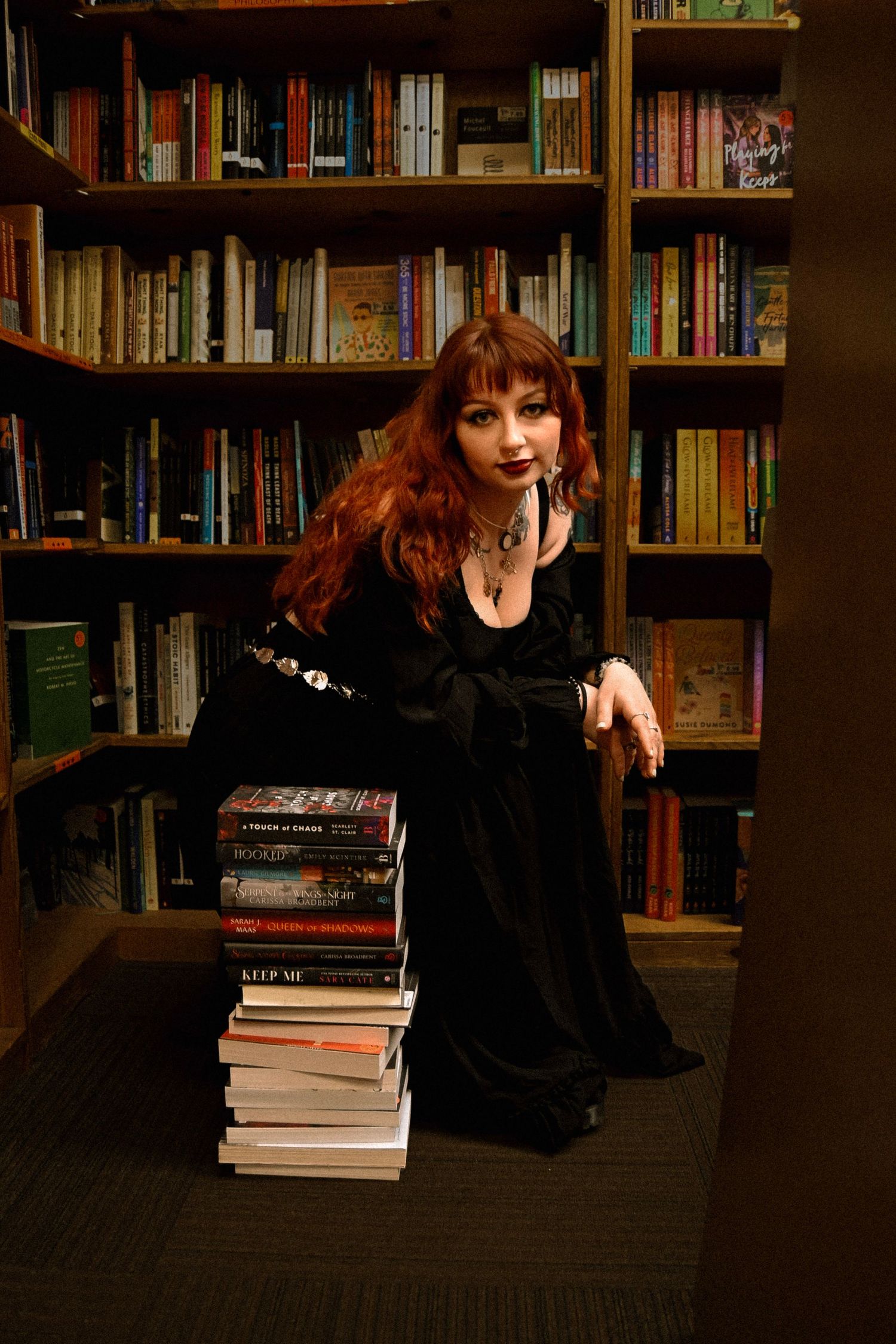 A series of five photos showing a person in black clothing crouching in front of library bookshelves with stacked books.