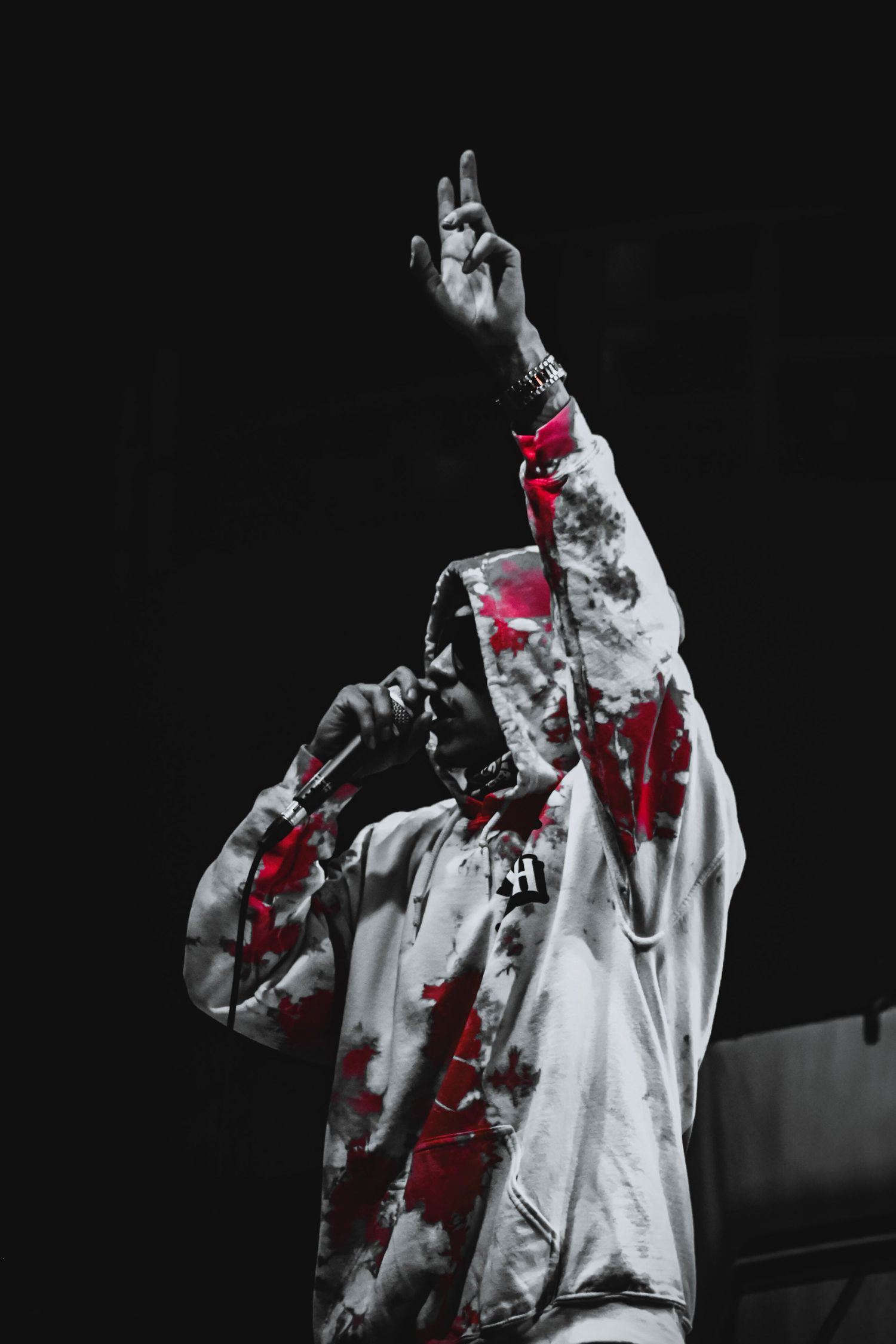 Black and white concert photo with red accents showing a performer holding a microphone.