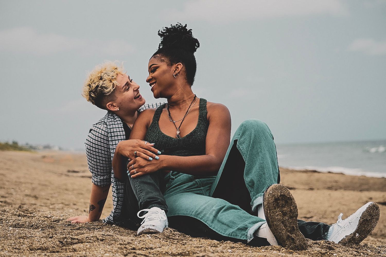 Couples lounging together on sandy beach with ocean in background.